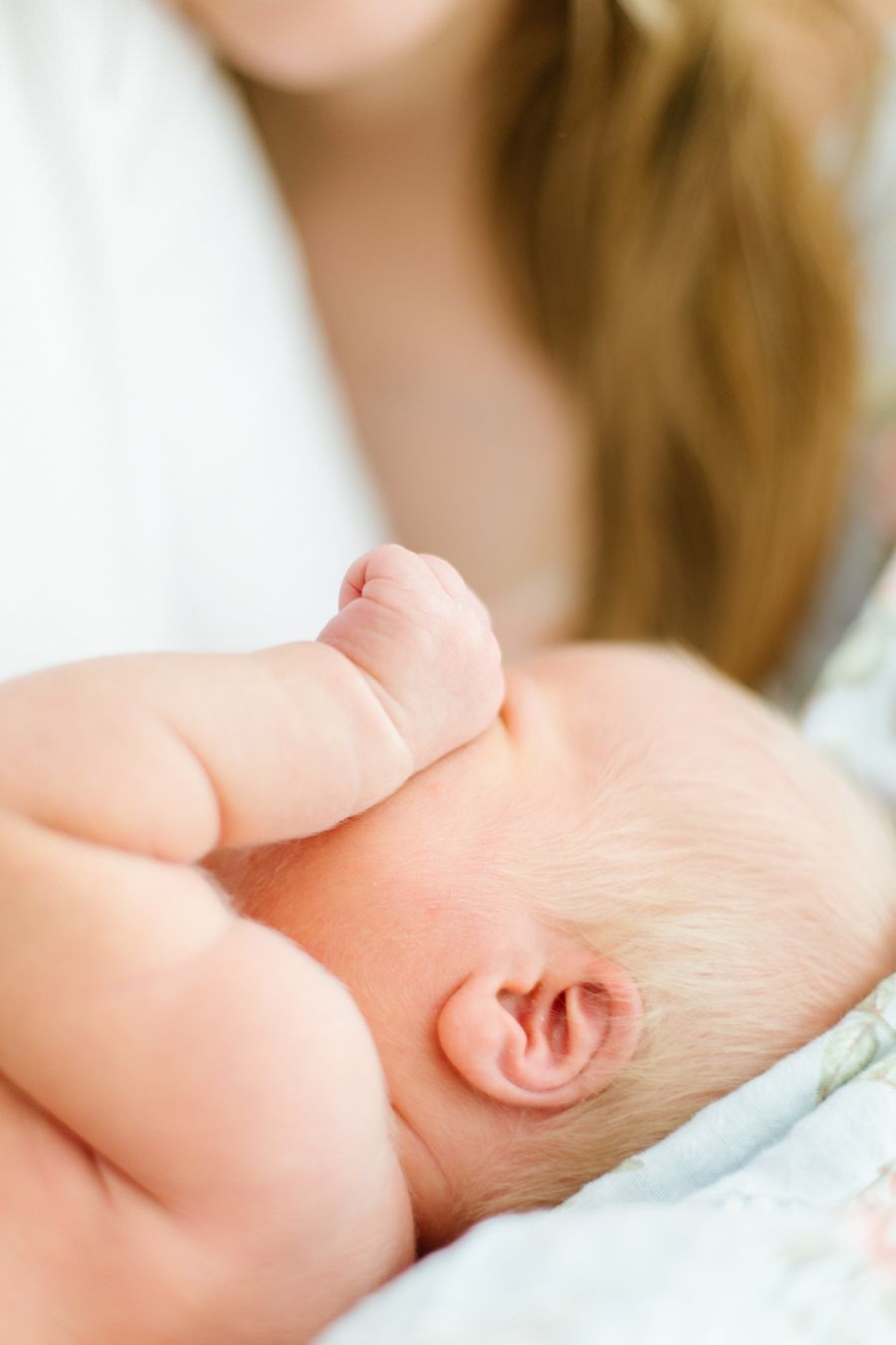 Vastasyntynyt pienokainen hieroo unisena silmiään newborn-kuvauksessa kotona. Vastasyntyneen kuvaus Lohjalla, Espoossa ja Uudellamaalla.