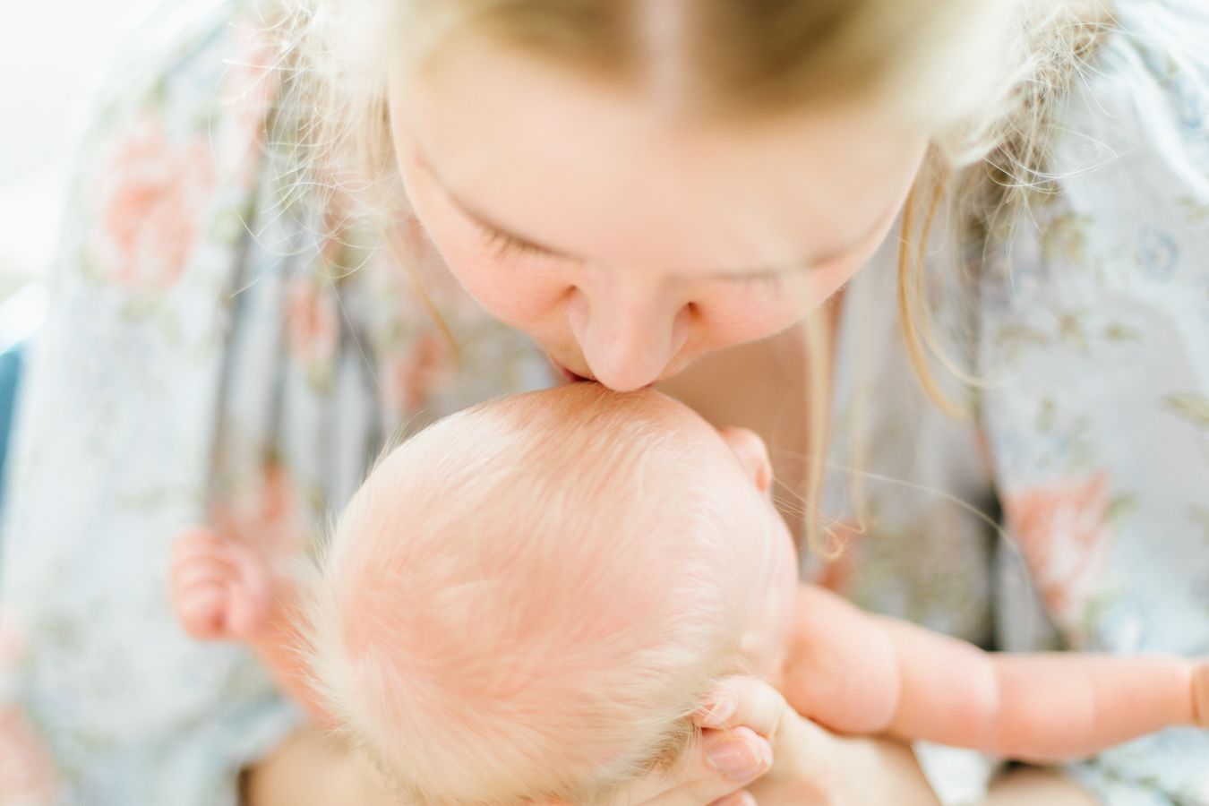 Äiti suukottaa vastasyntynyttä pienokaista newborn-kuvauksessa perheen kotona. Newborn-kuvaus Lohja, Espoo ja muu Uusimaa.