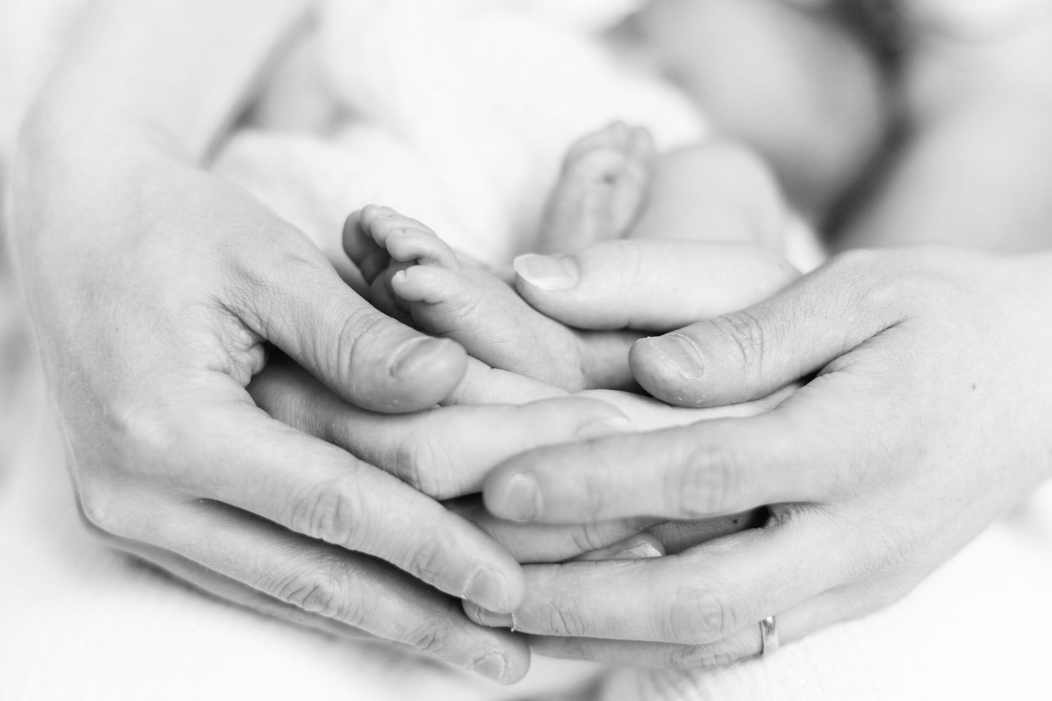 Vastasyntyneen pikkuruiset jalat vanhempien käsissä newborn-kuvauksessa studiossa Vantaalla.