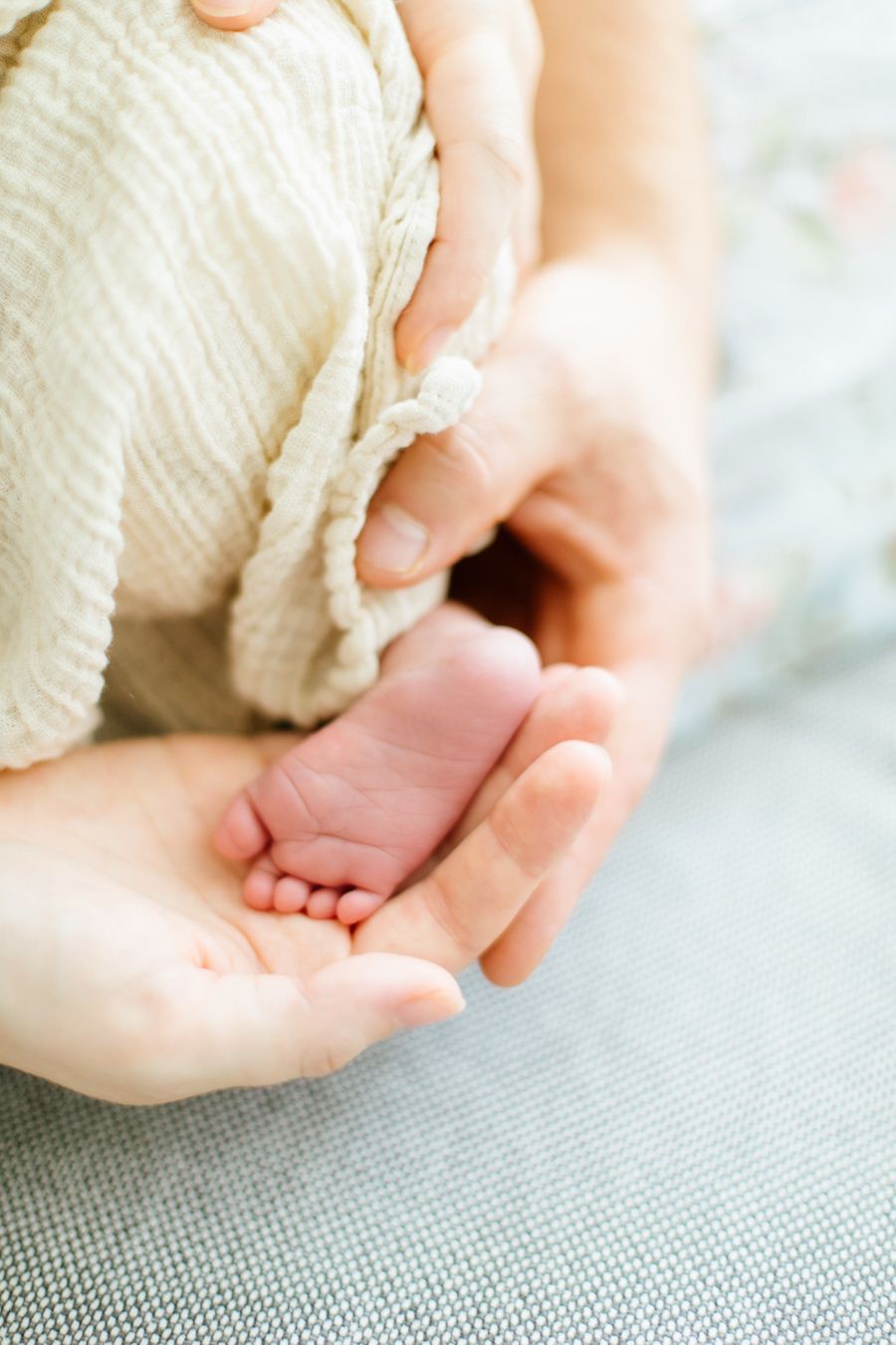 Vastasyntynyt vauva perheensä sylissä kotisohvalla – lifestyle-kuvaus perheen omassa kodissa Lohjalla.