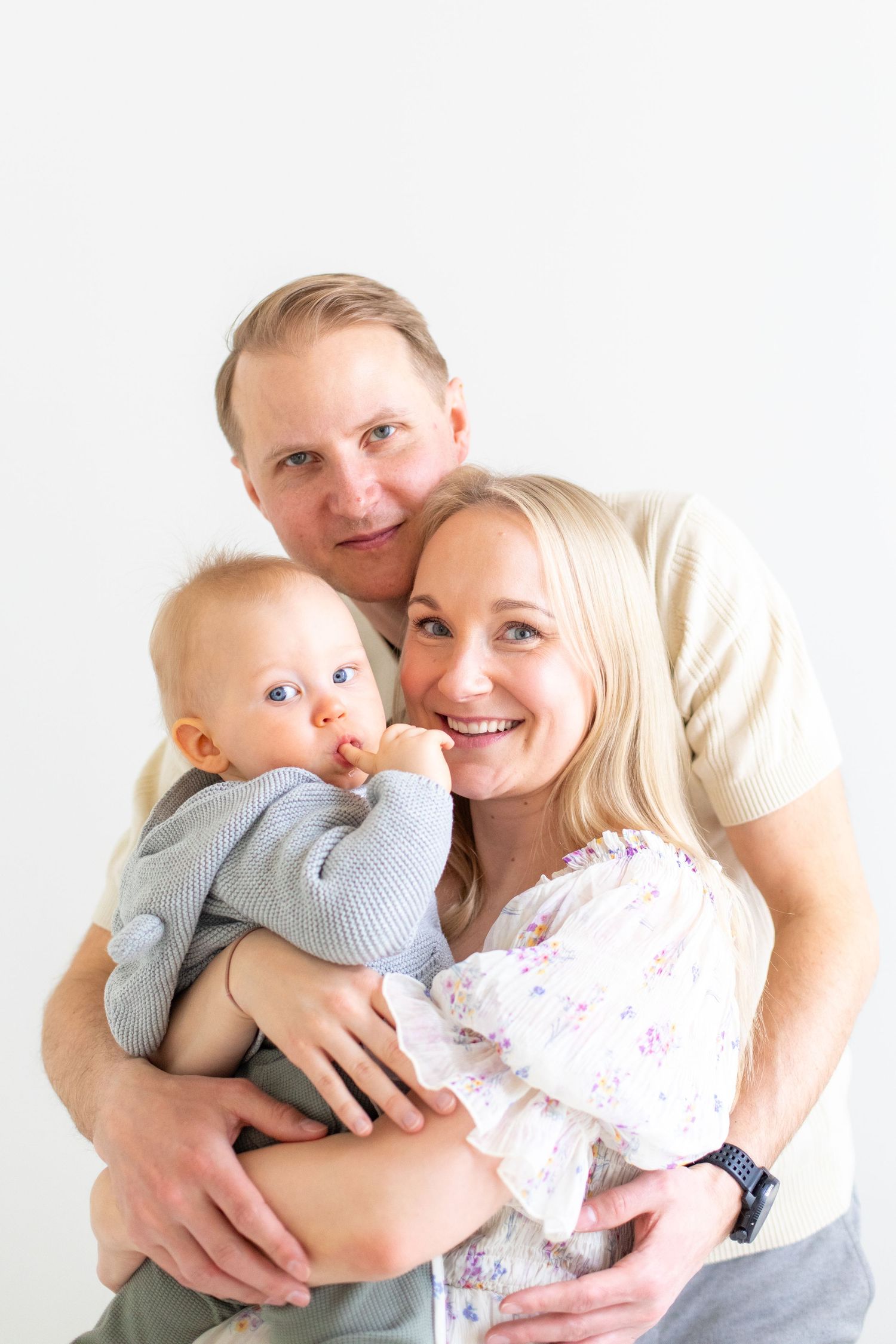 Äiti, isä ja yksivuotias lapsi yksivuotiskuvauksessa studiossa Vantaalla.