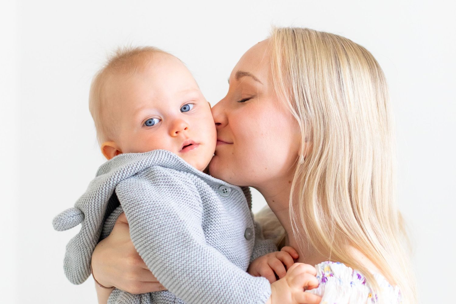 Äiti suukottaa yksivuotiasta yksivuotiskuvauksessa studiossa Vantaalla.