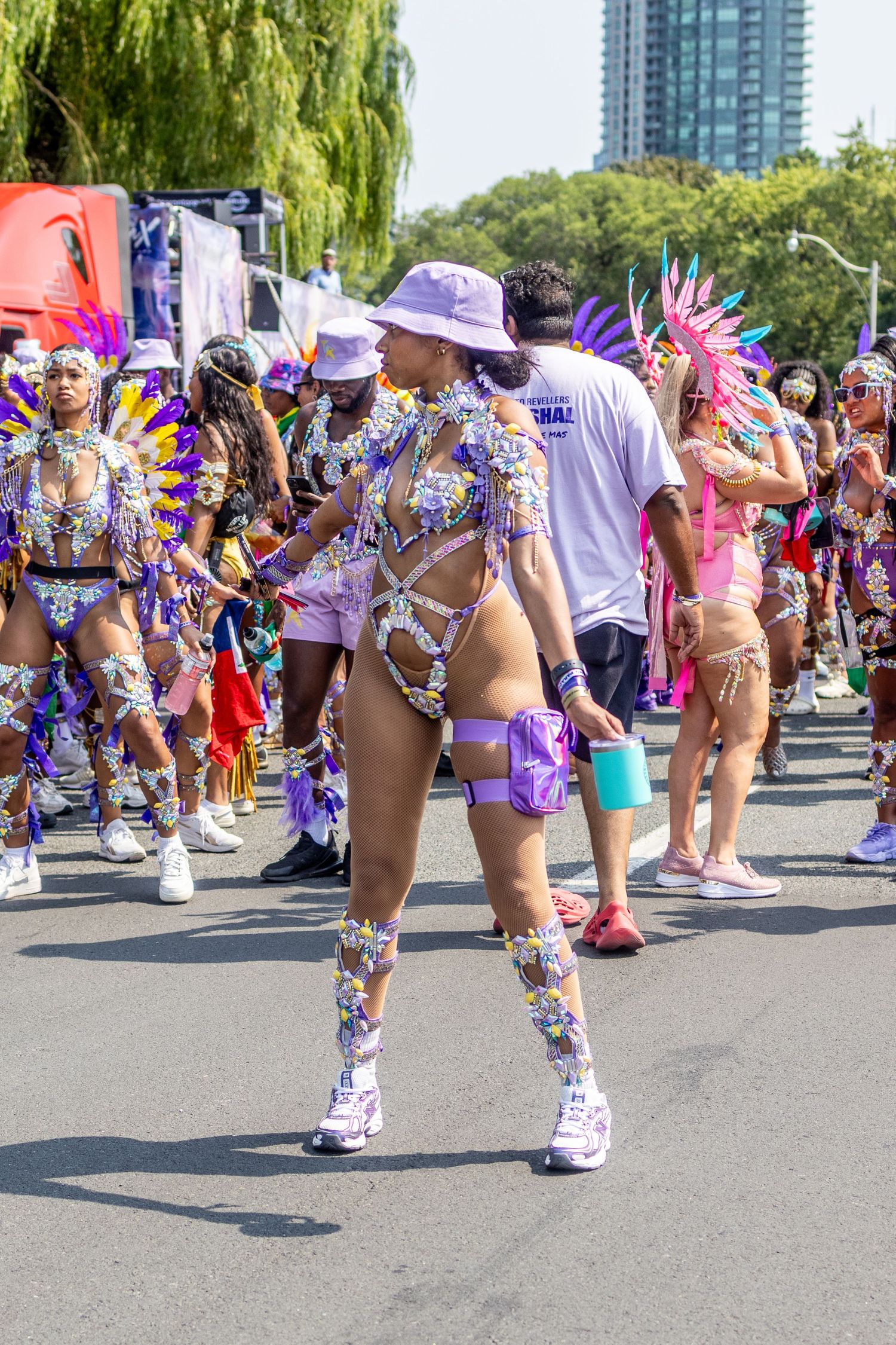 Carnival parade participants in purple and gold costumes dancing in the street.