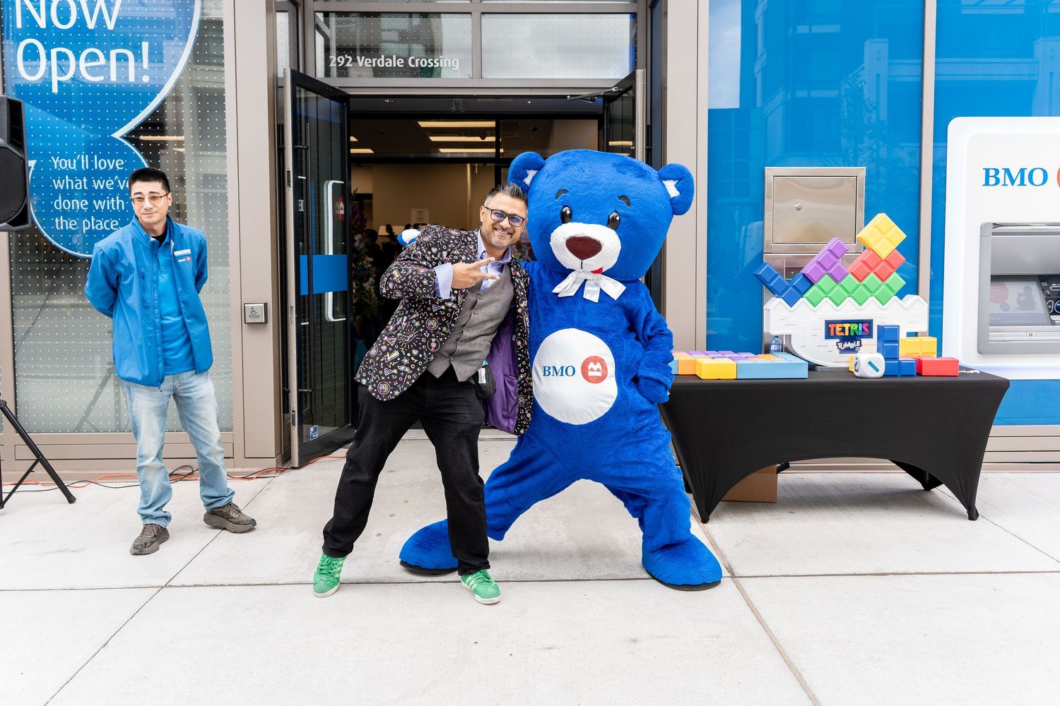 Man posing with BMO blue bear mascot outside newly opened BMO bank branch.