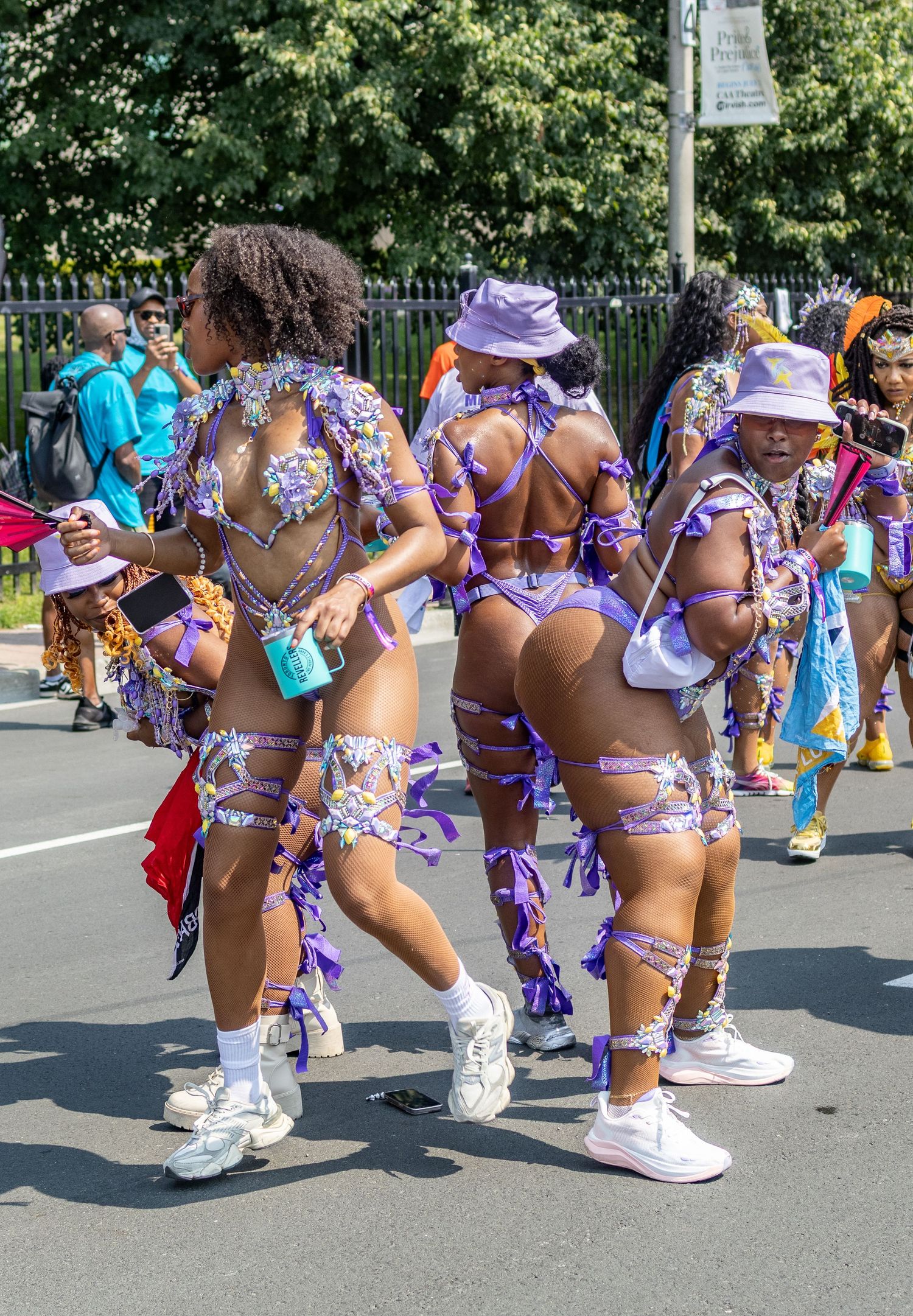Group of women in matching purple carnival costumes walking in a street parade.