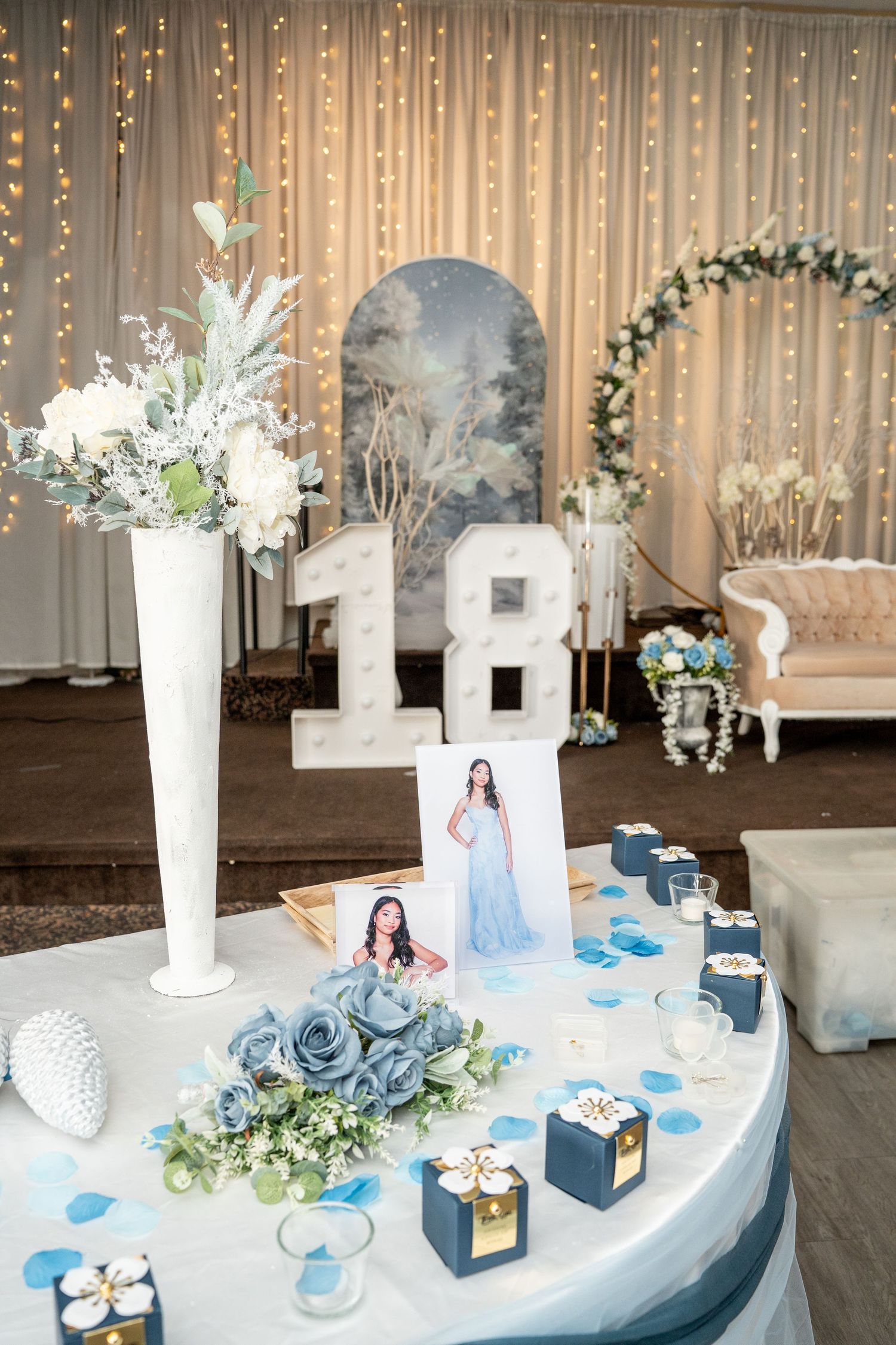 Elegant debut party table display with blue roses, number 18 marquee lights, and birthday girl portrait.