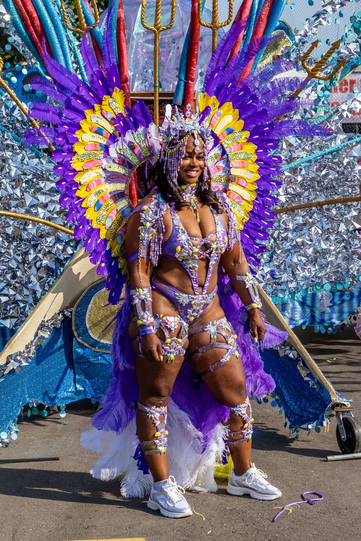 Woman in stunning purple feathered carnival queen costume with elaborate headdress at street parade.