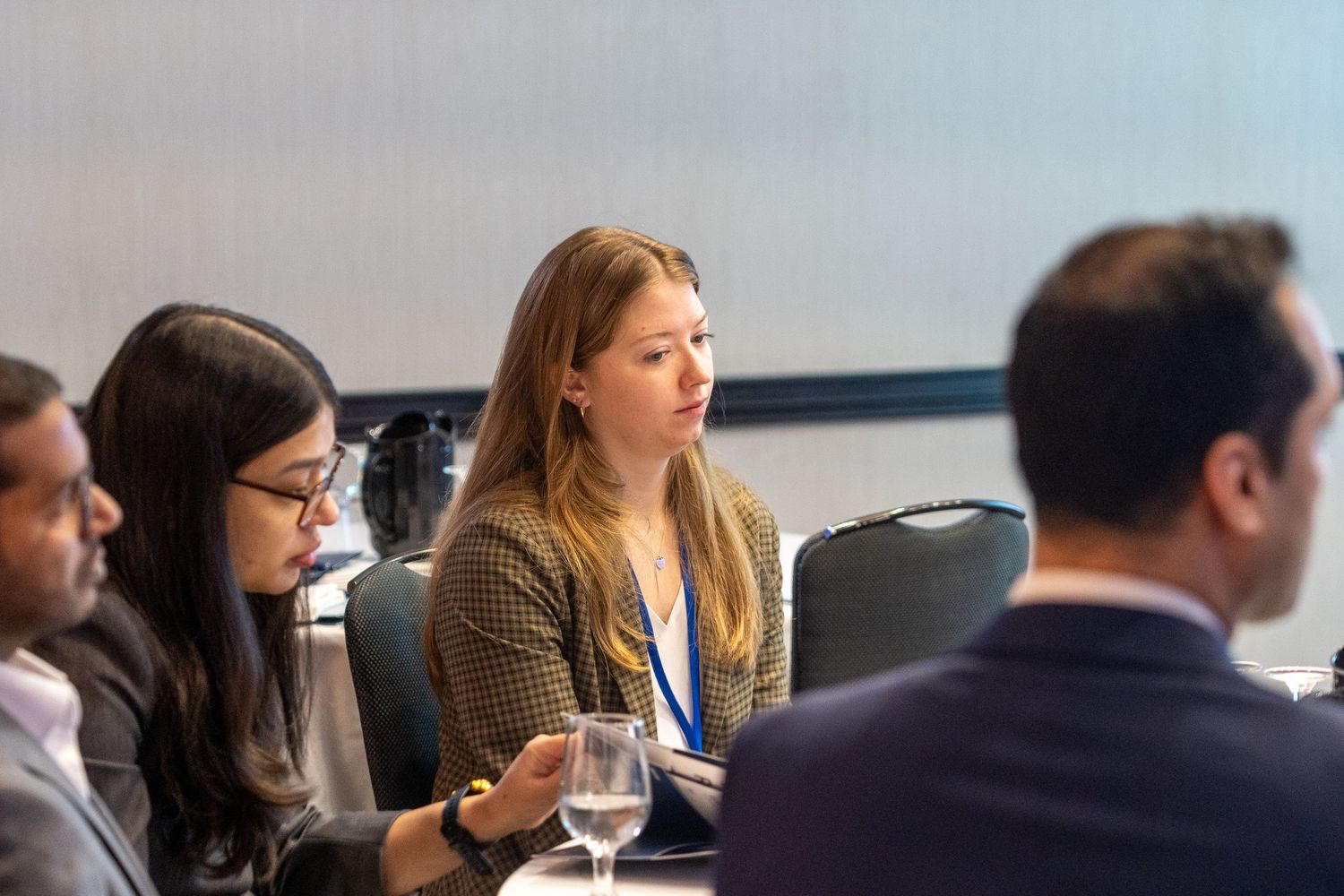 Attendees listening attentively at a professional business conference seated at round tables.