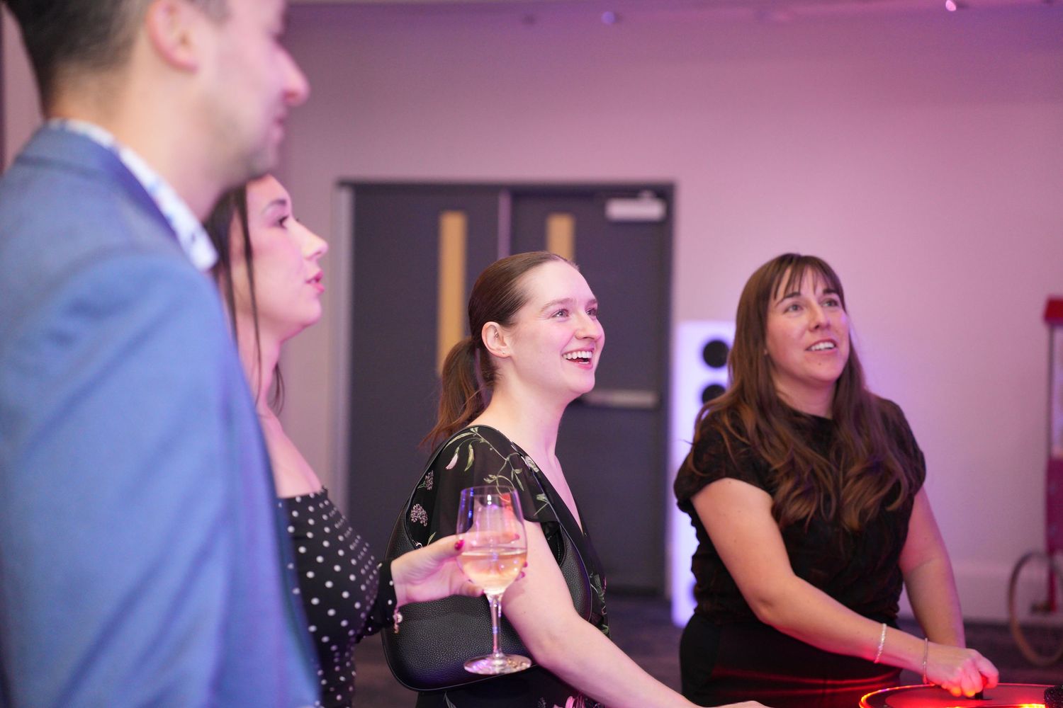 Women laughing and holding wine glasses at a stylish corporate networking event.