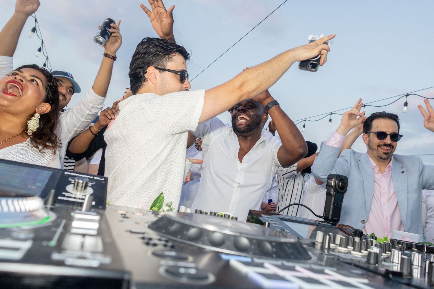DJ and guests dancing and celebrating at a lively outdoor rooftop party.