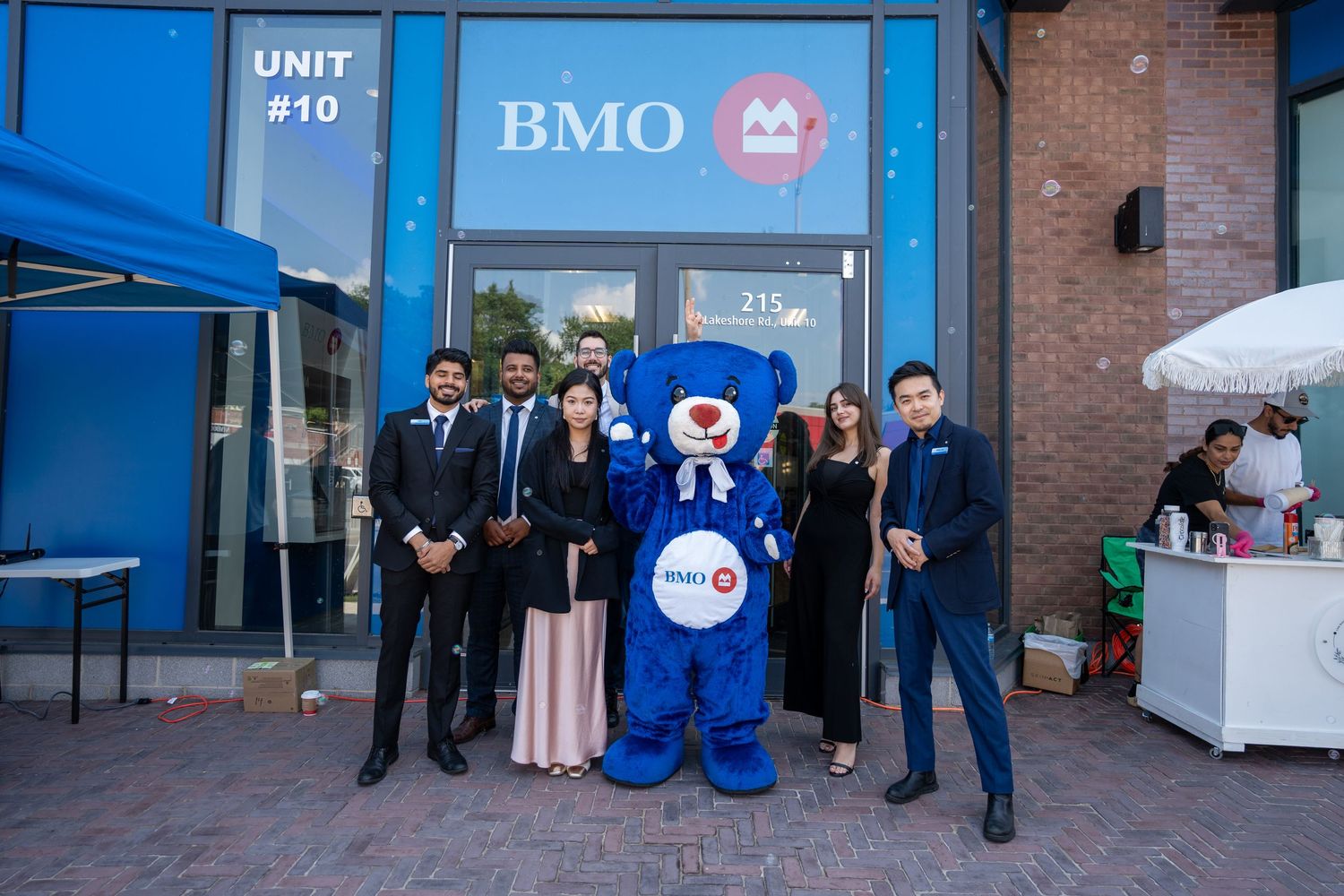 BMO bank team posing with blue bear mascot outside Unit 10 BMO branch.