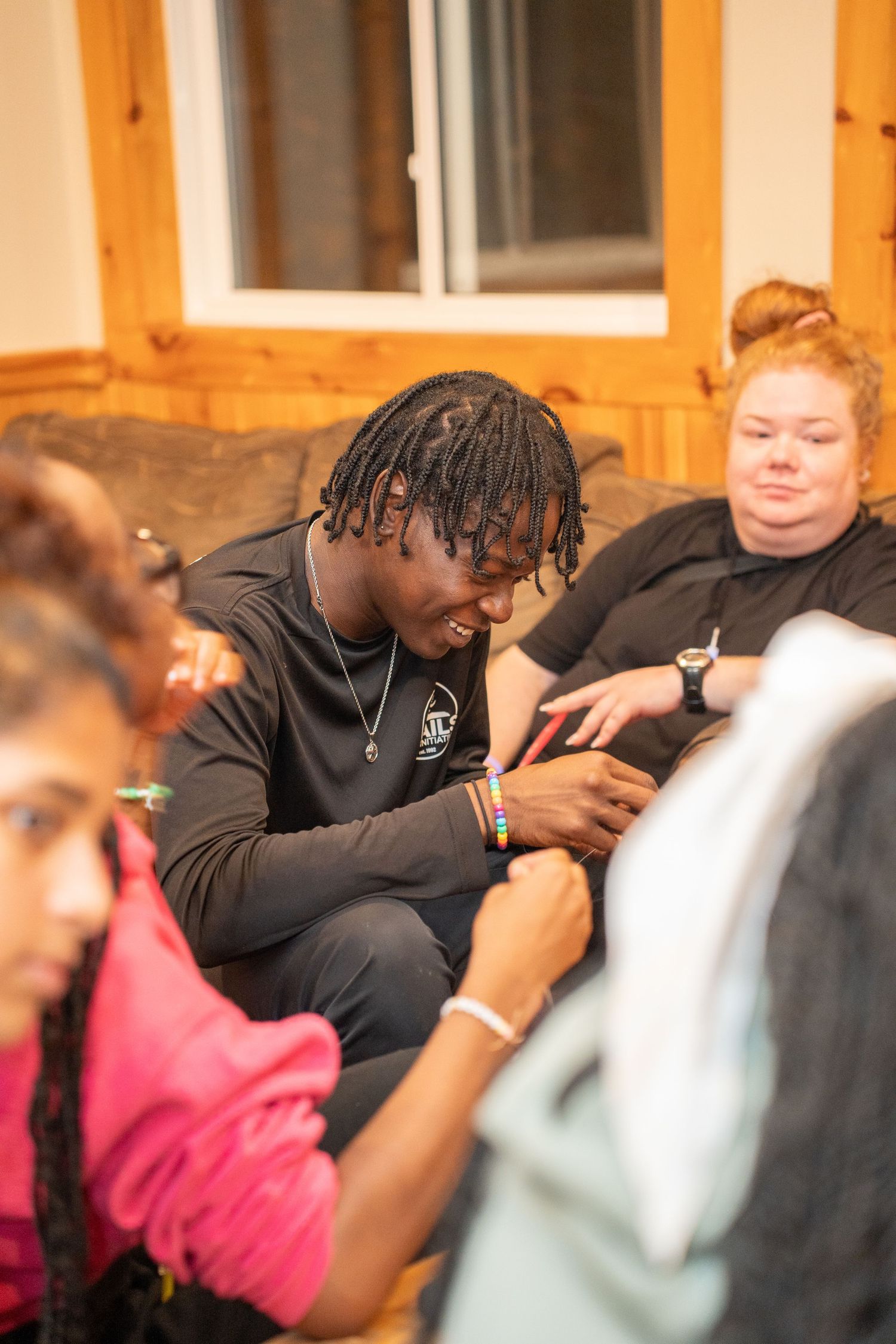 Group of young people sitting together on a couch engaged in casual indoor activity.