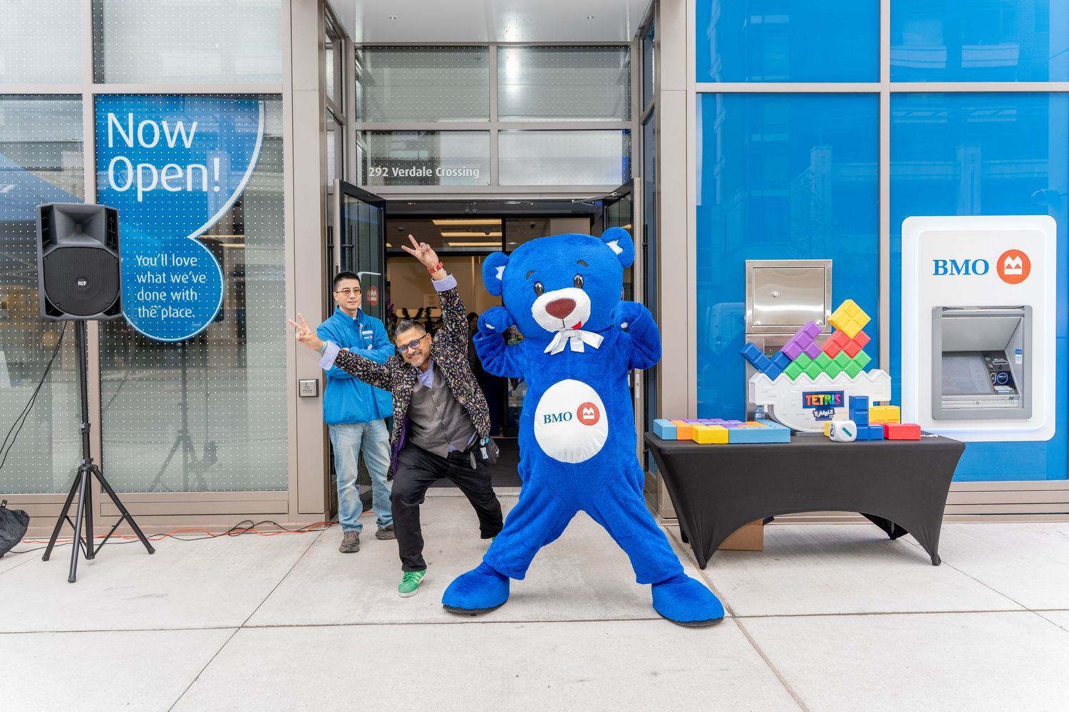 BMO mascot bear poses with staff member outside newly opened BMO bank branch location.