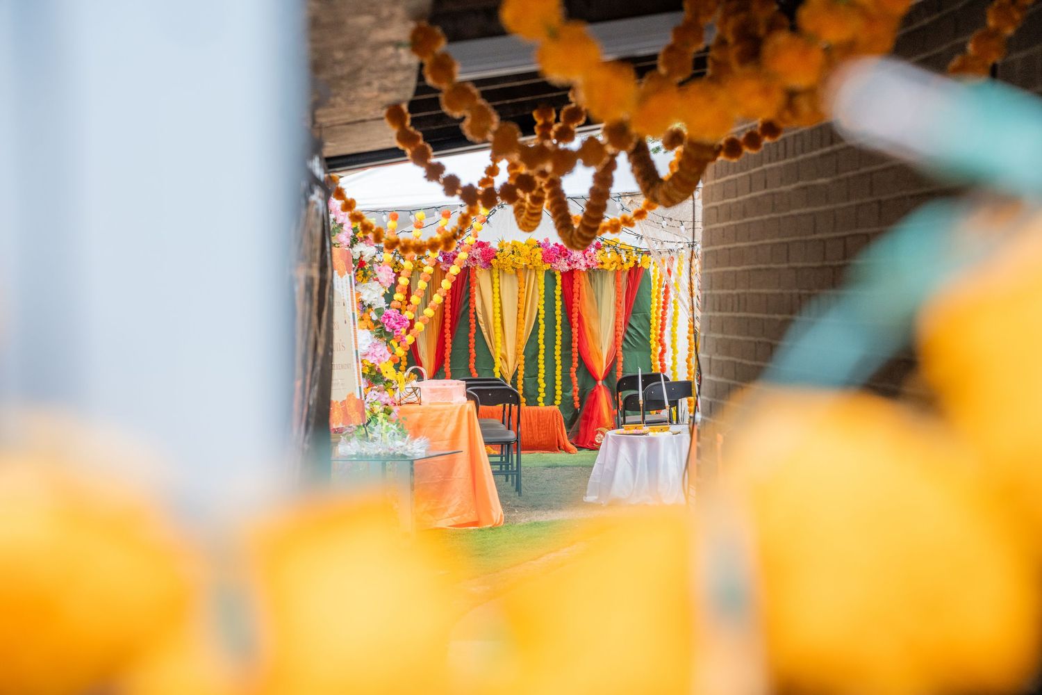 Colorful Indian wedding Haldi ceremony venue decorated with marigold garlands and vibrant drapes.
