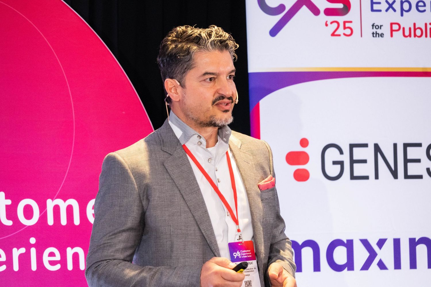 Male speaker presenting at CXS 2025 Experience for the Public conference with Genesys branding.