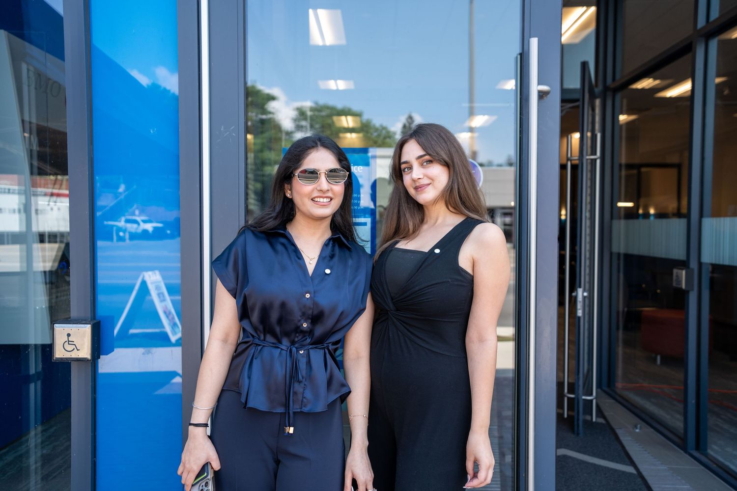 Two women smiling and posing together outside a BMO bank location.