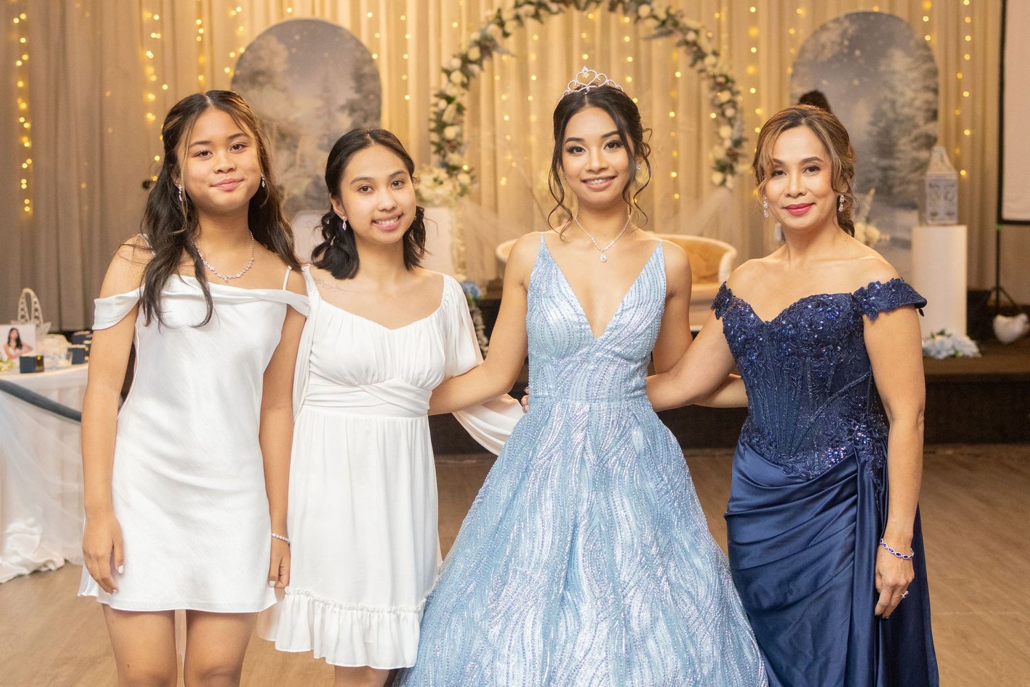 Birthday debutante in blue gown poses with family members at her elegant 18th birthday celebration.
