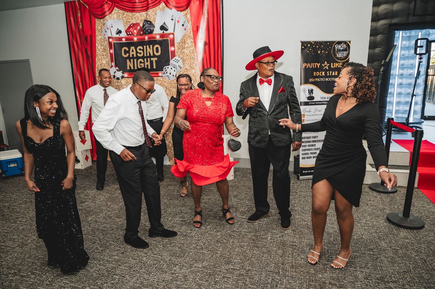 Event space decorated with red curtains and casino-themed signage featuring guests in formal wear.