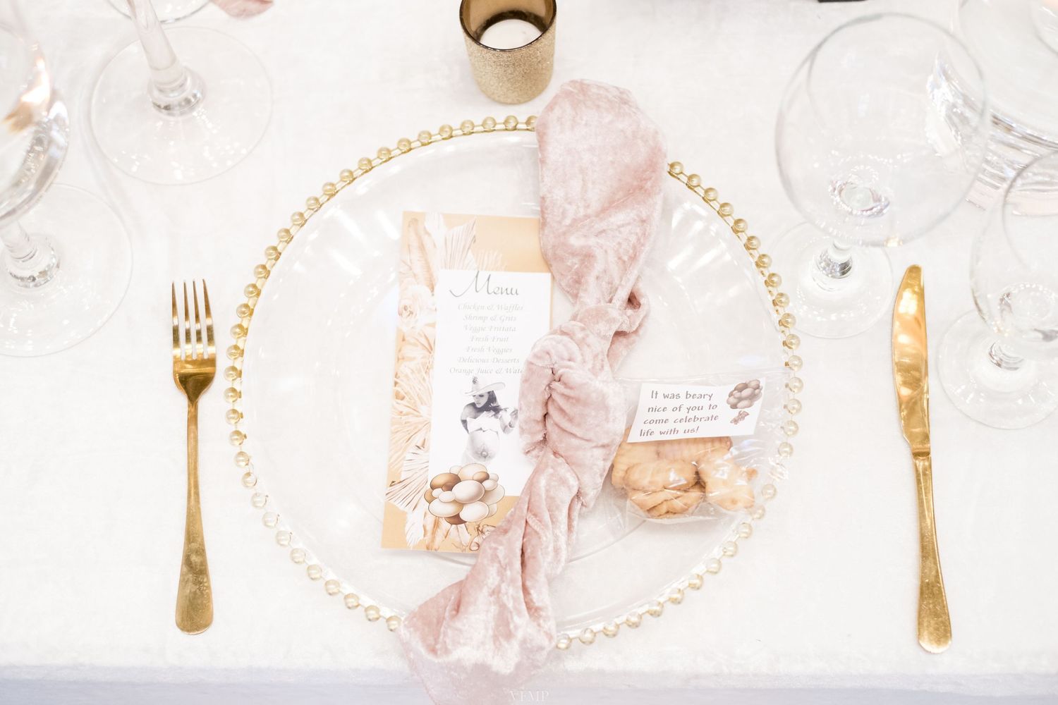 Elegant place setting with gold utensils and pink accents on white marble featuring a romantic vintage napkin design.
