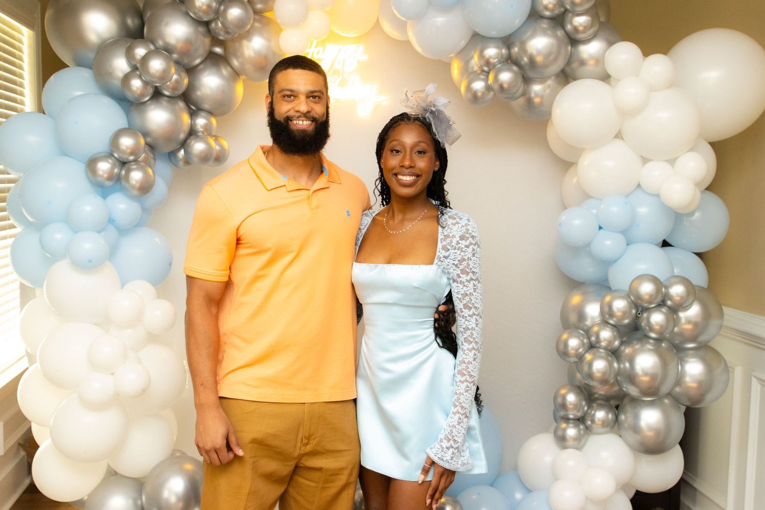 Elegant baby shower setup featuring silver and white balloon arrangements with guests posing.