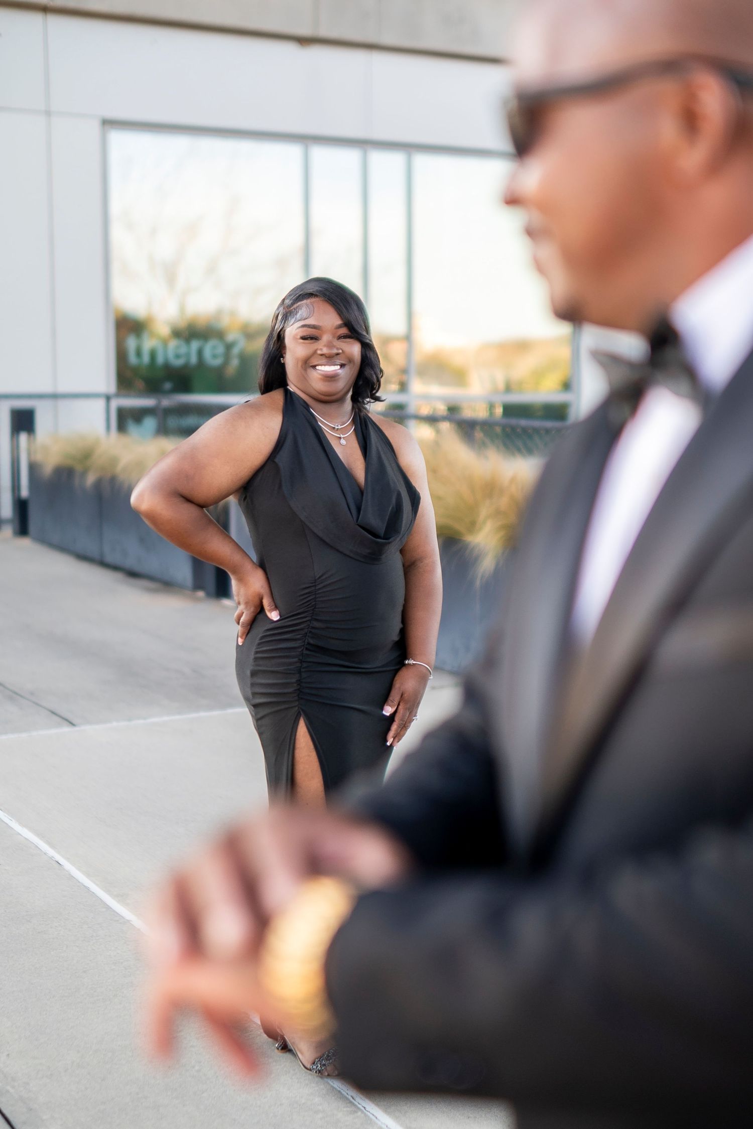 Professional business photoshoot of people in formal attire interacting outdoors at an office building.