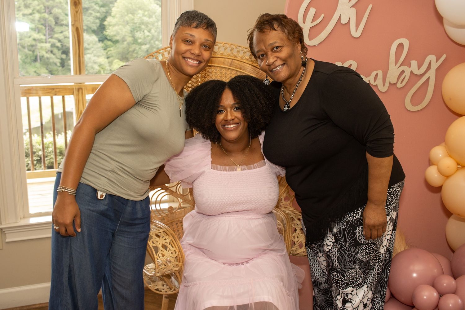 A baby shower celebration with pink balloons and decor as guests gather for photos and festivities.