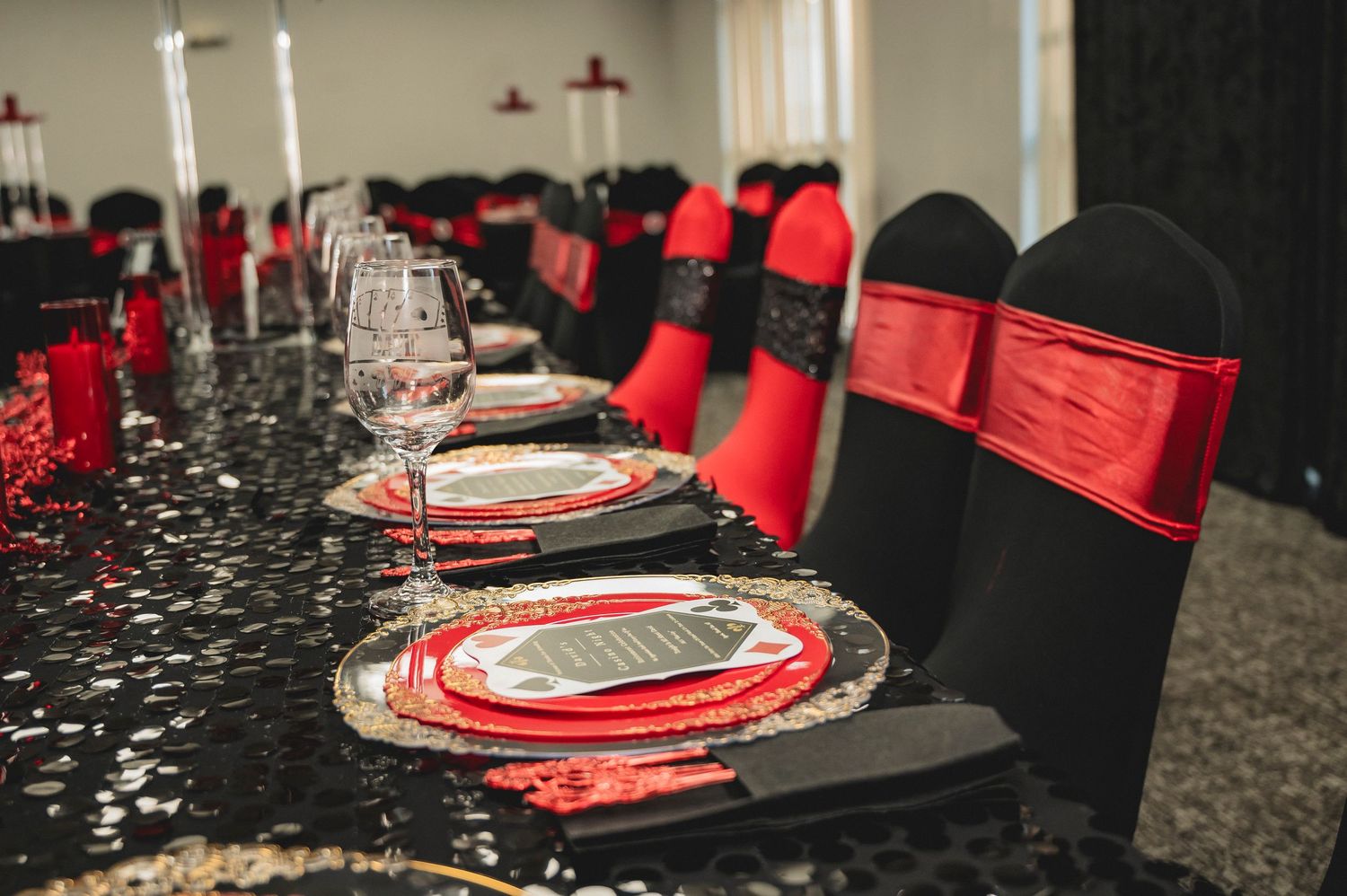 Elegant table setting with red and black color scheme featuring wine glasses and place settings.