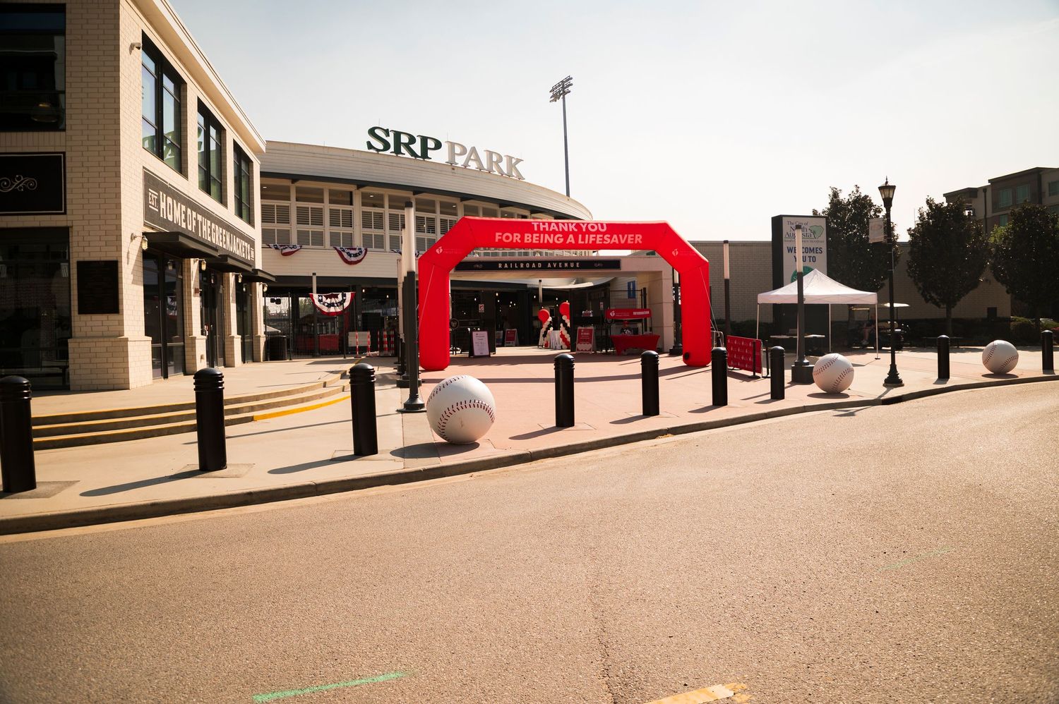 SRP Park stadium entrance with red arch, bollards, and open plaza on a sunny day.