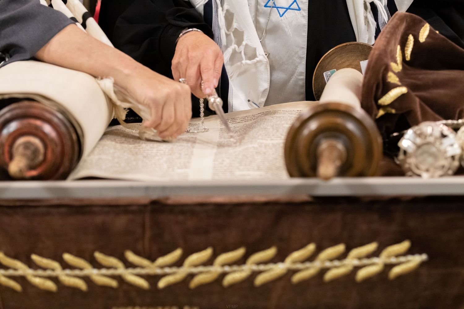Torah scrolls lie unrolled on a wooden table during a traditional Jewish religious ceremony.