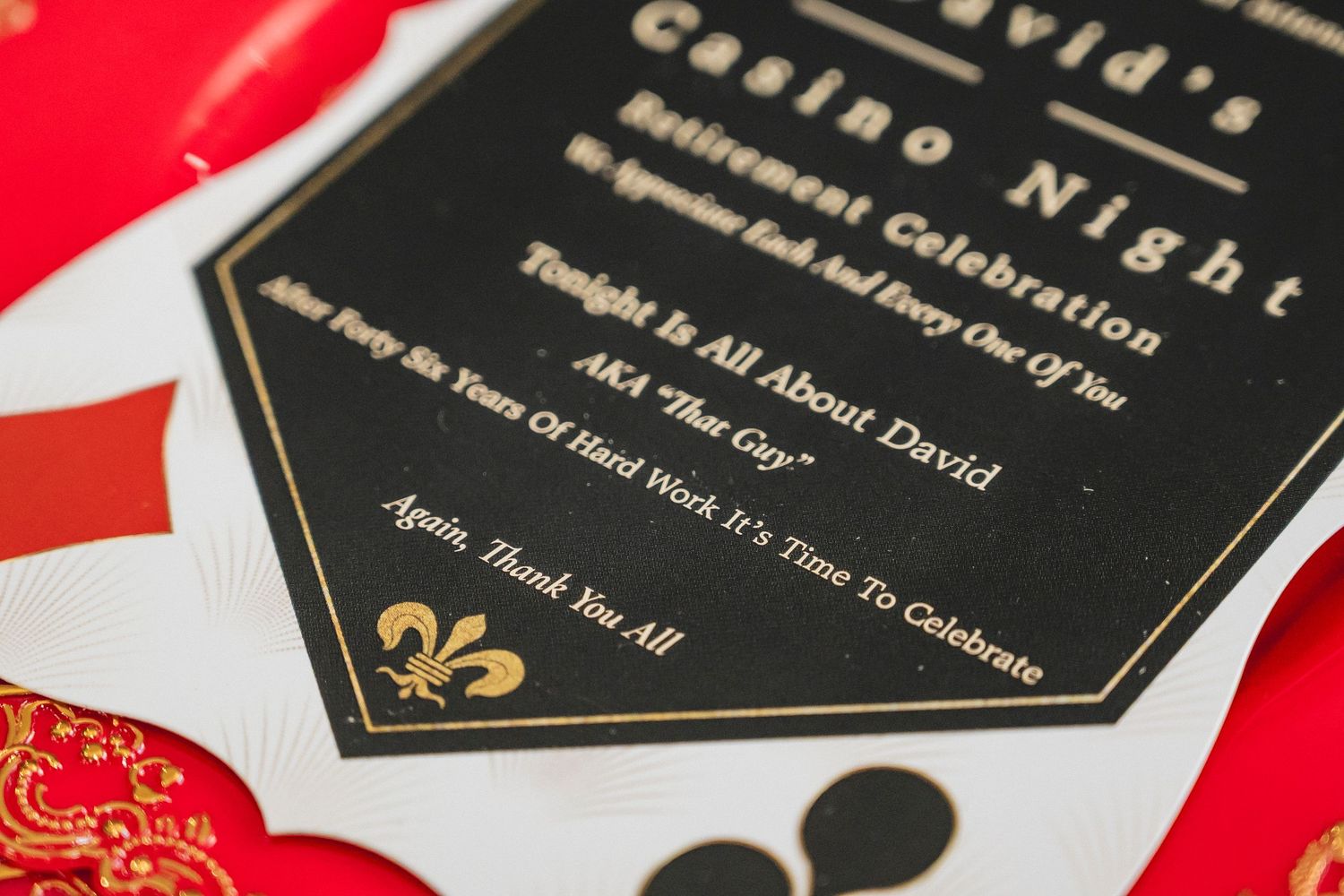 Close-up of black and gold casino night celebration invitation with playing card design elements.