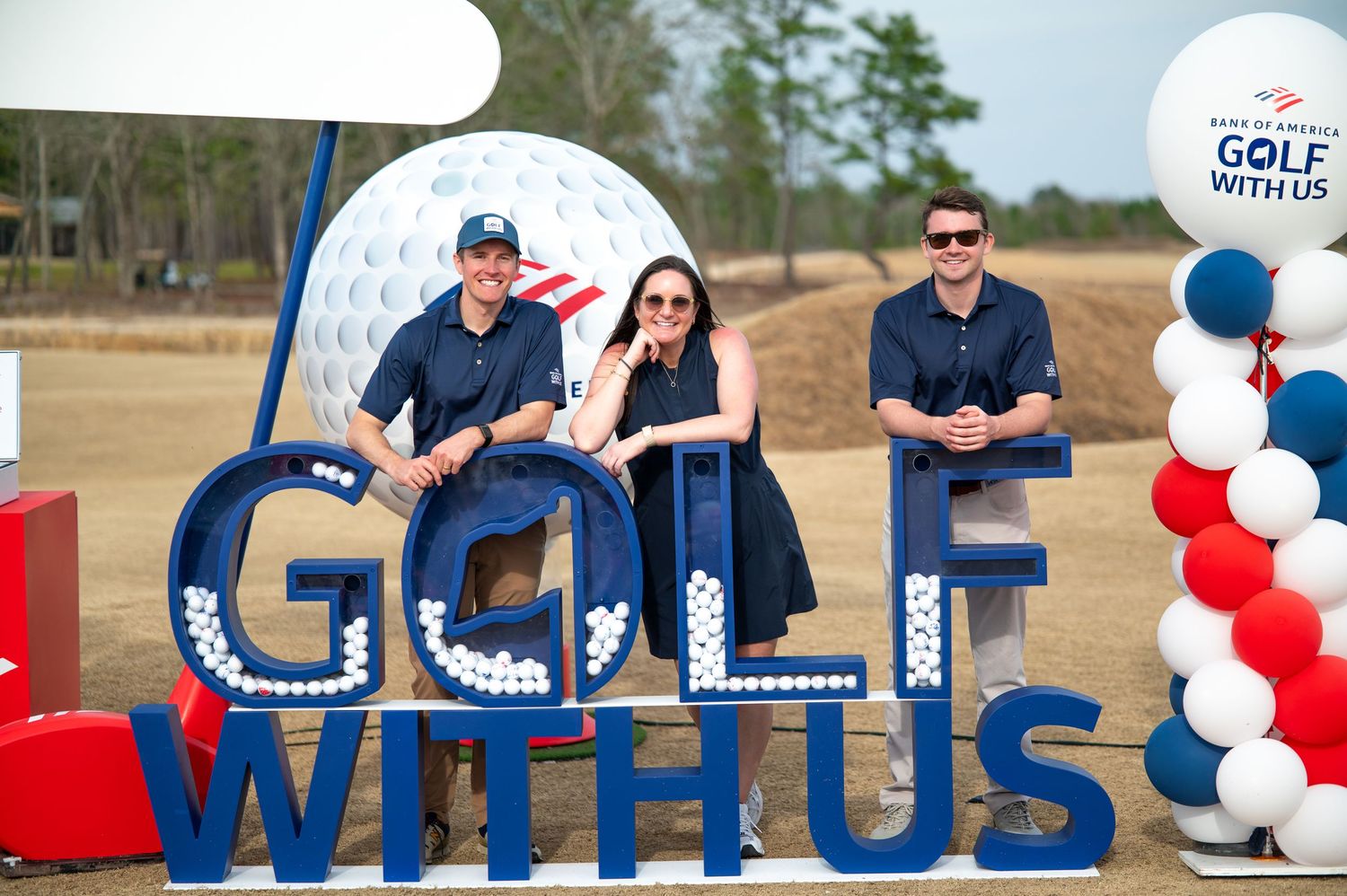 A festive red, white and blue balloon arch display with letter signage spells out 'CELEBRATE WITH US' at an outdoor event.