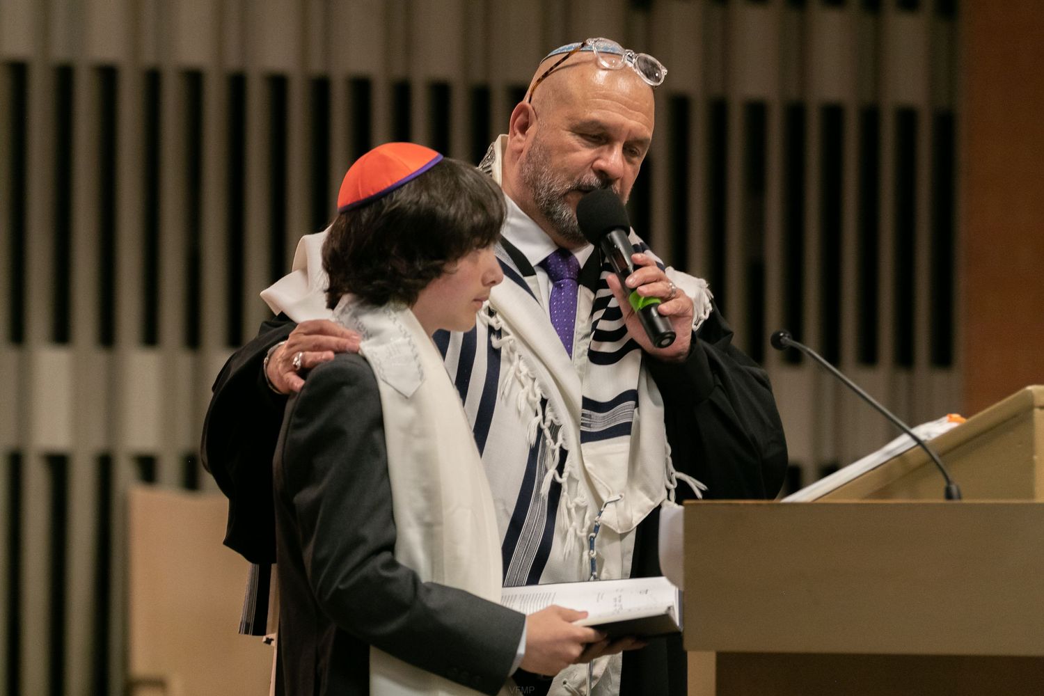 Religious figures participate in Jewish prayer service wearing traditional tallit prayer shawls and kippot.