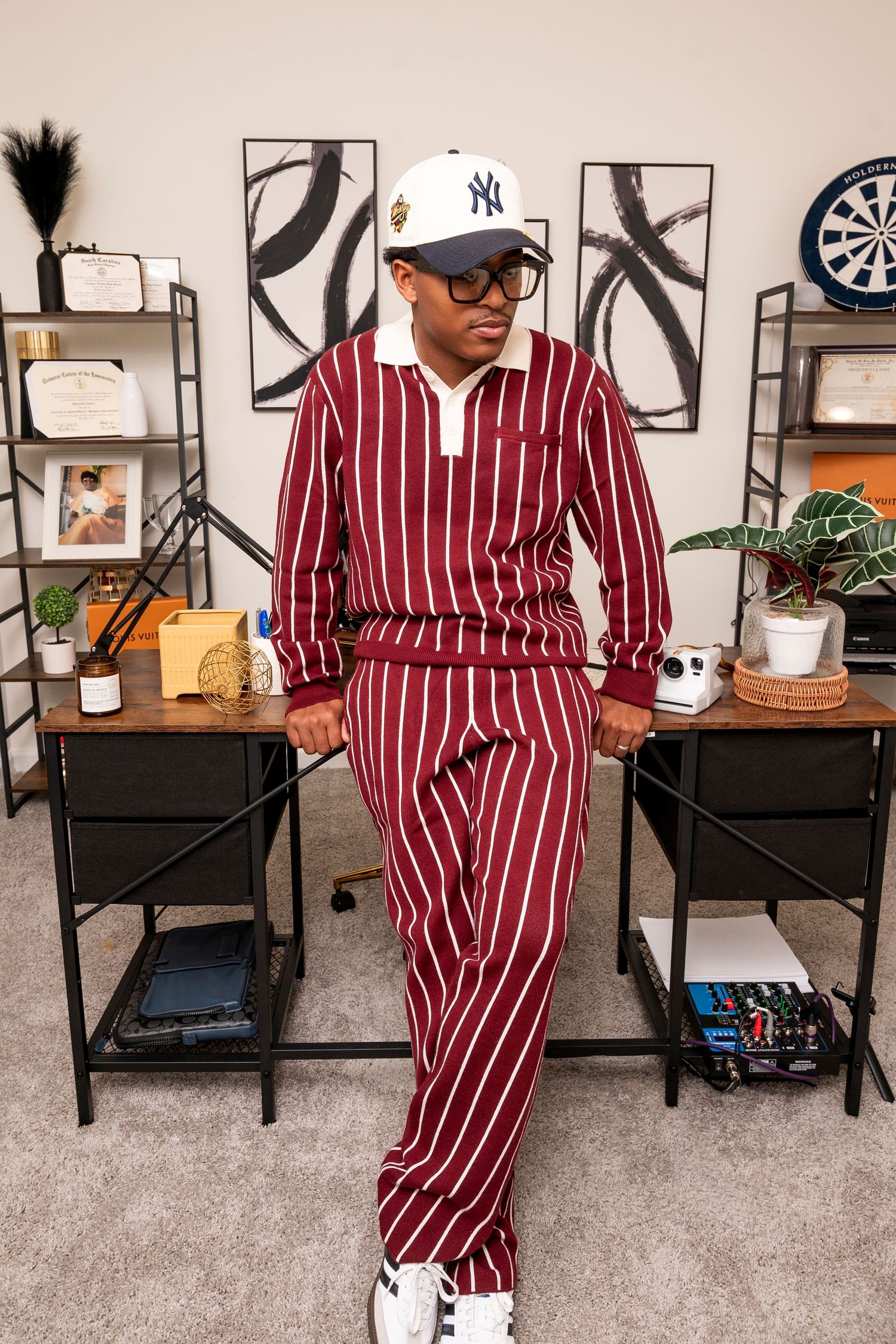 Modern room interior with red and white striped loungewear, Yankees cap, black shelving units and abstract wall art.