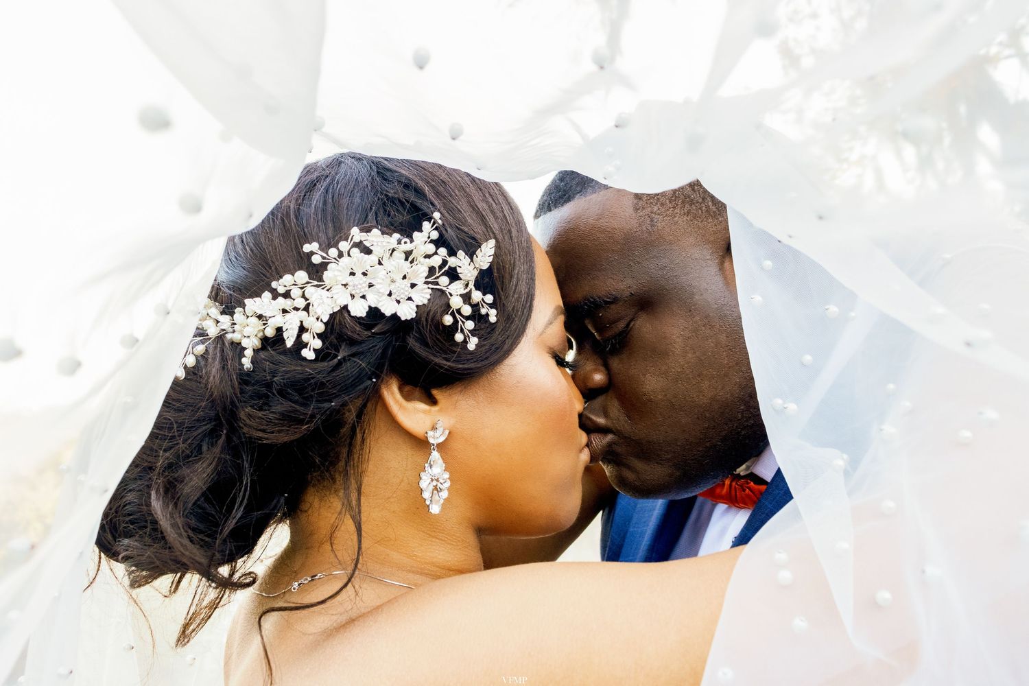 A romantic newlywed couple shares a tender kiss during their outdoor wedding celebration.