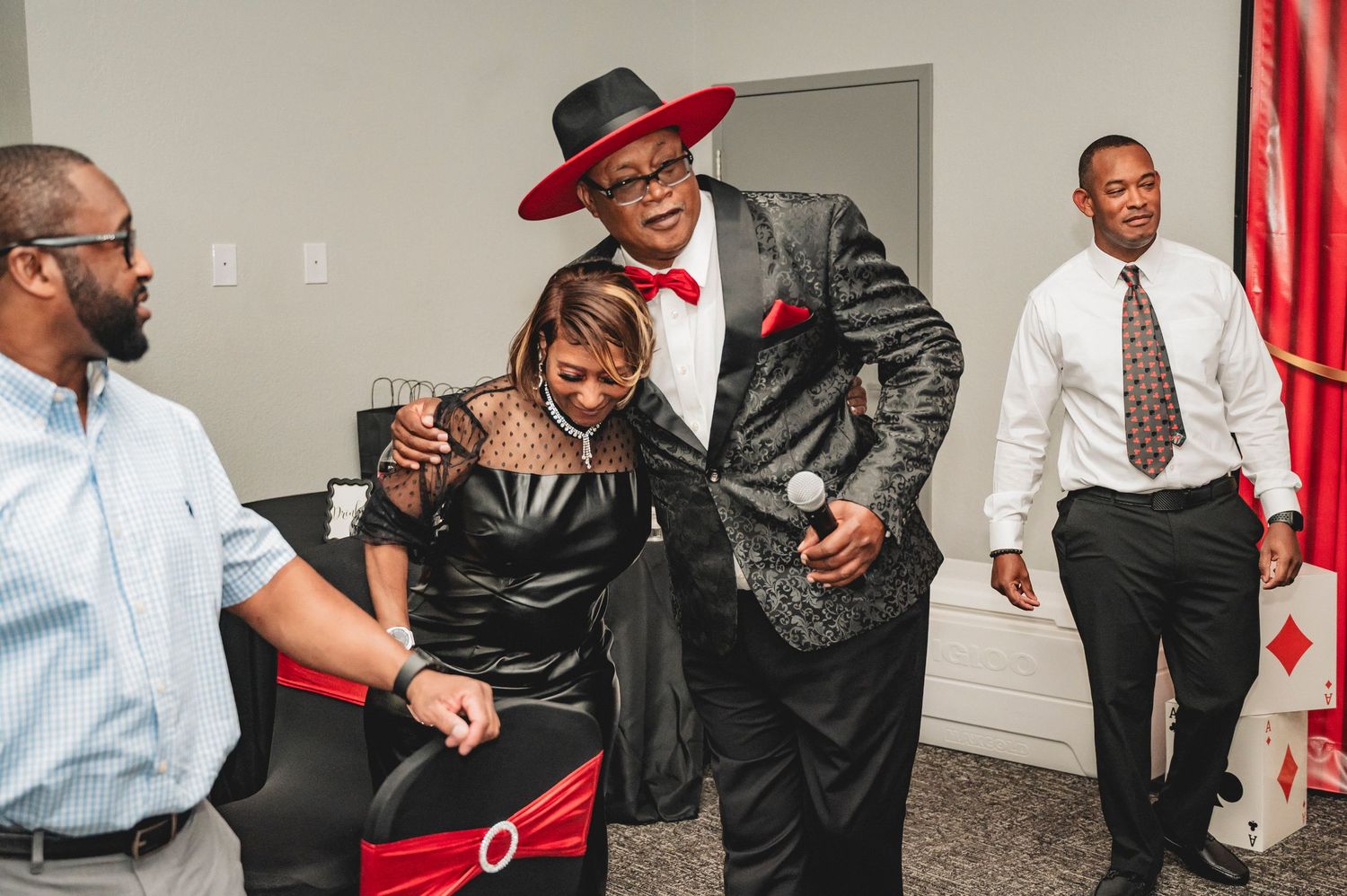 Guests interacting at a casino night party wearing formal attire and red accessories.