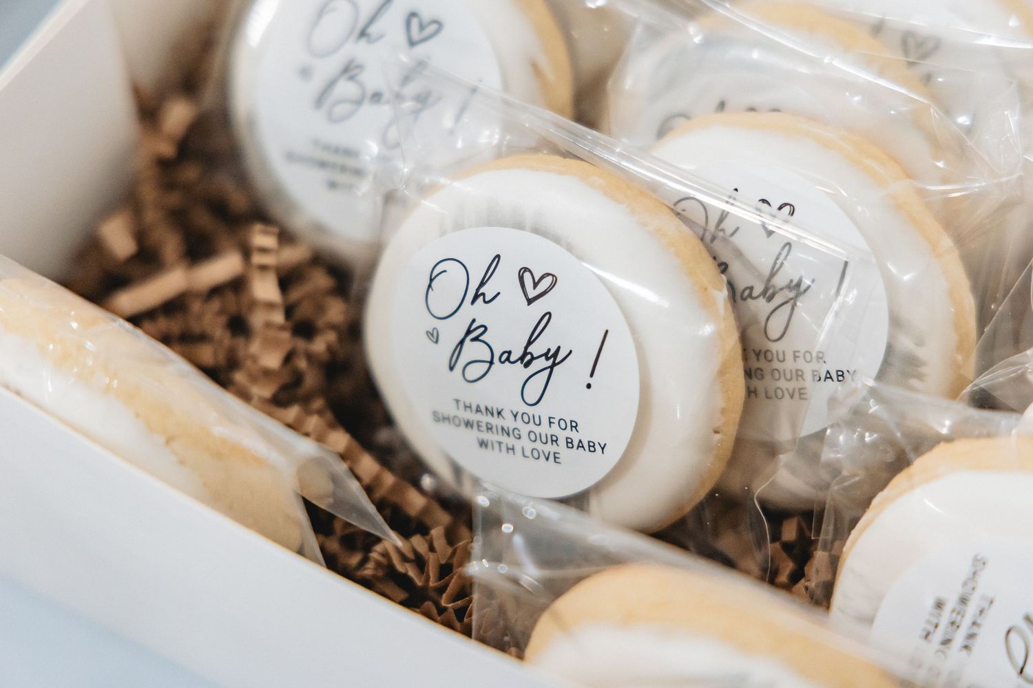 White favor boxes with bows arranged in rows against shimmery silver background for wedding favors.