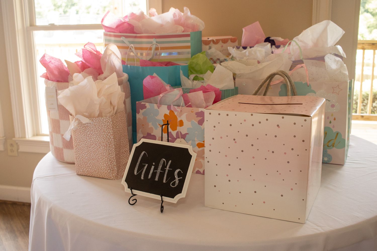 Pink and white gift bags and boxes arranged on a white table for a party or celebration.