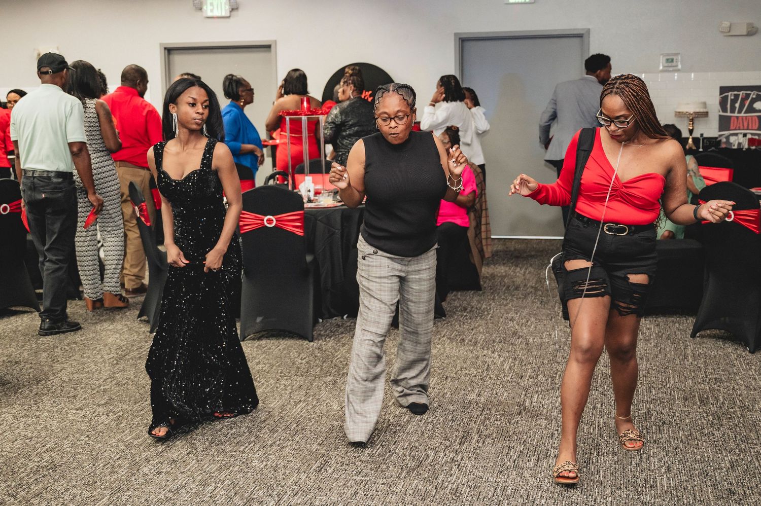 People dancing and socializing at a casino-themed party decorated in red and black.