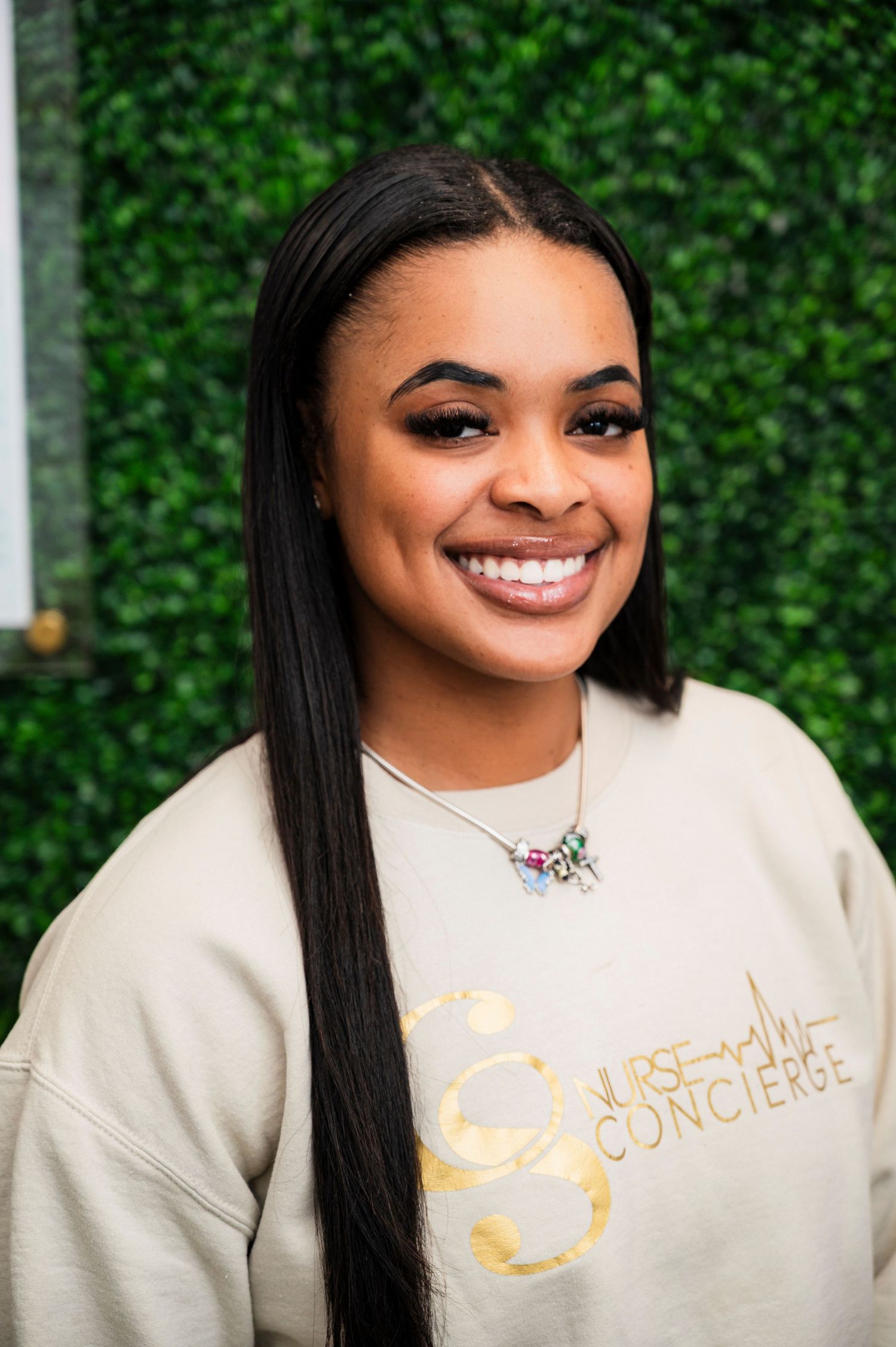 A series of five portrait shots against a green hedge background showing someone wearing a cream colored sweatshirt.