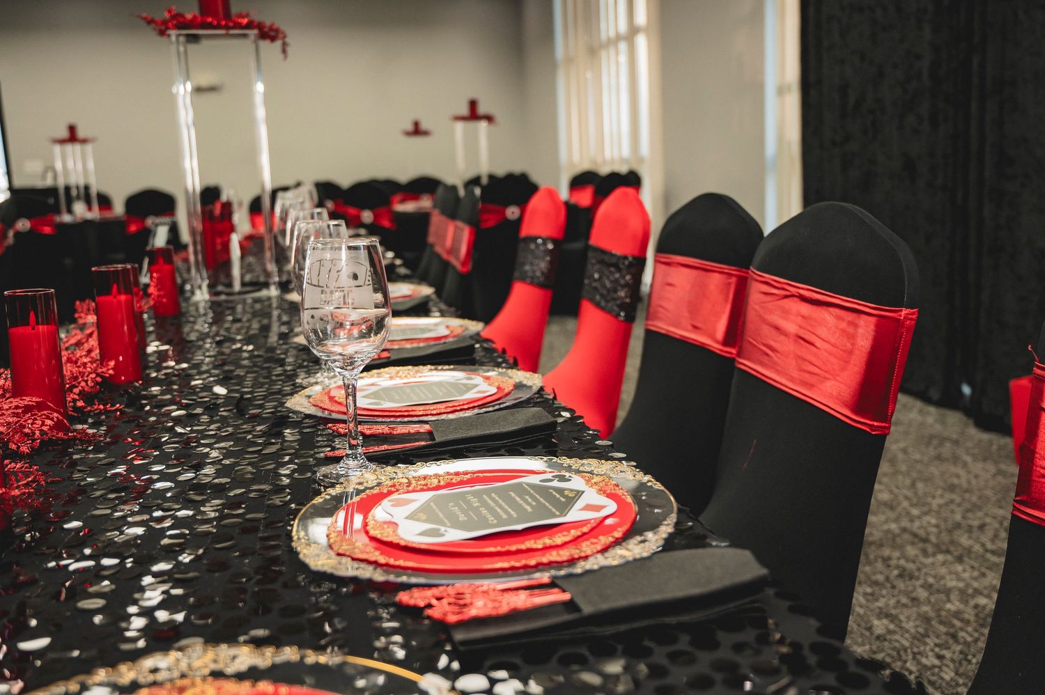 Formal table settings in red and black with elegant place settings and wine glasses.