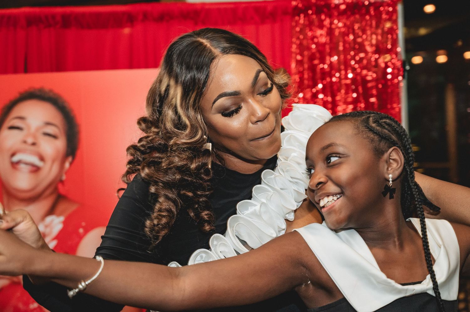 Party guests enjoying a celebration with joyful expressions and laughter against a red-lit backdrop with sparkles.