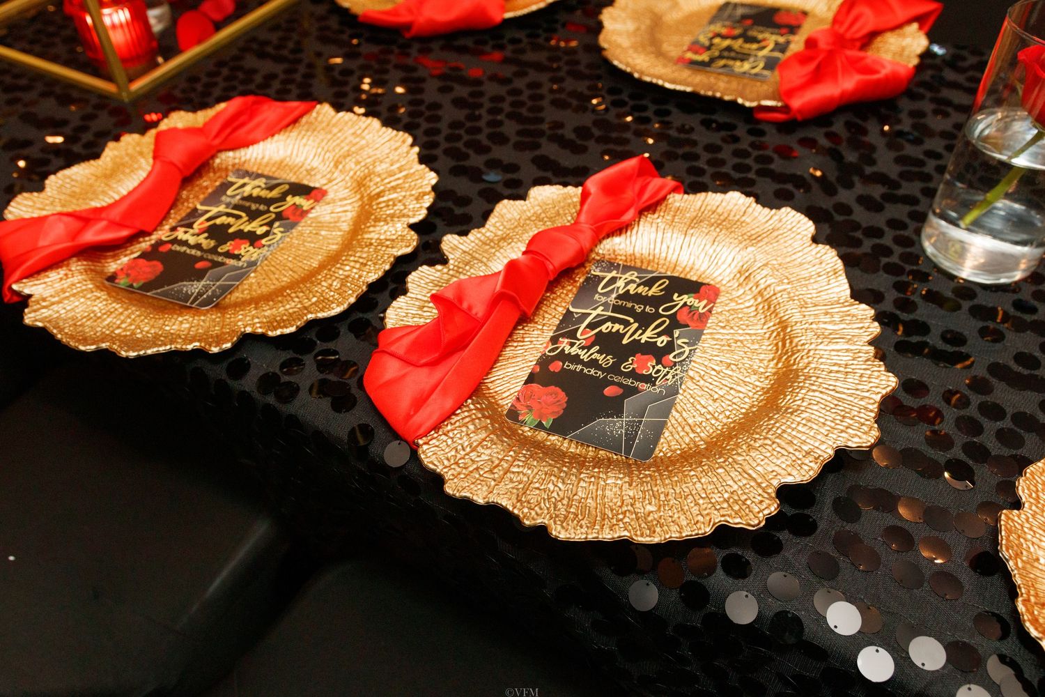 A decorative gold fabric with red ribbon sits on a dark surface with holiday decor in the background.