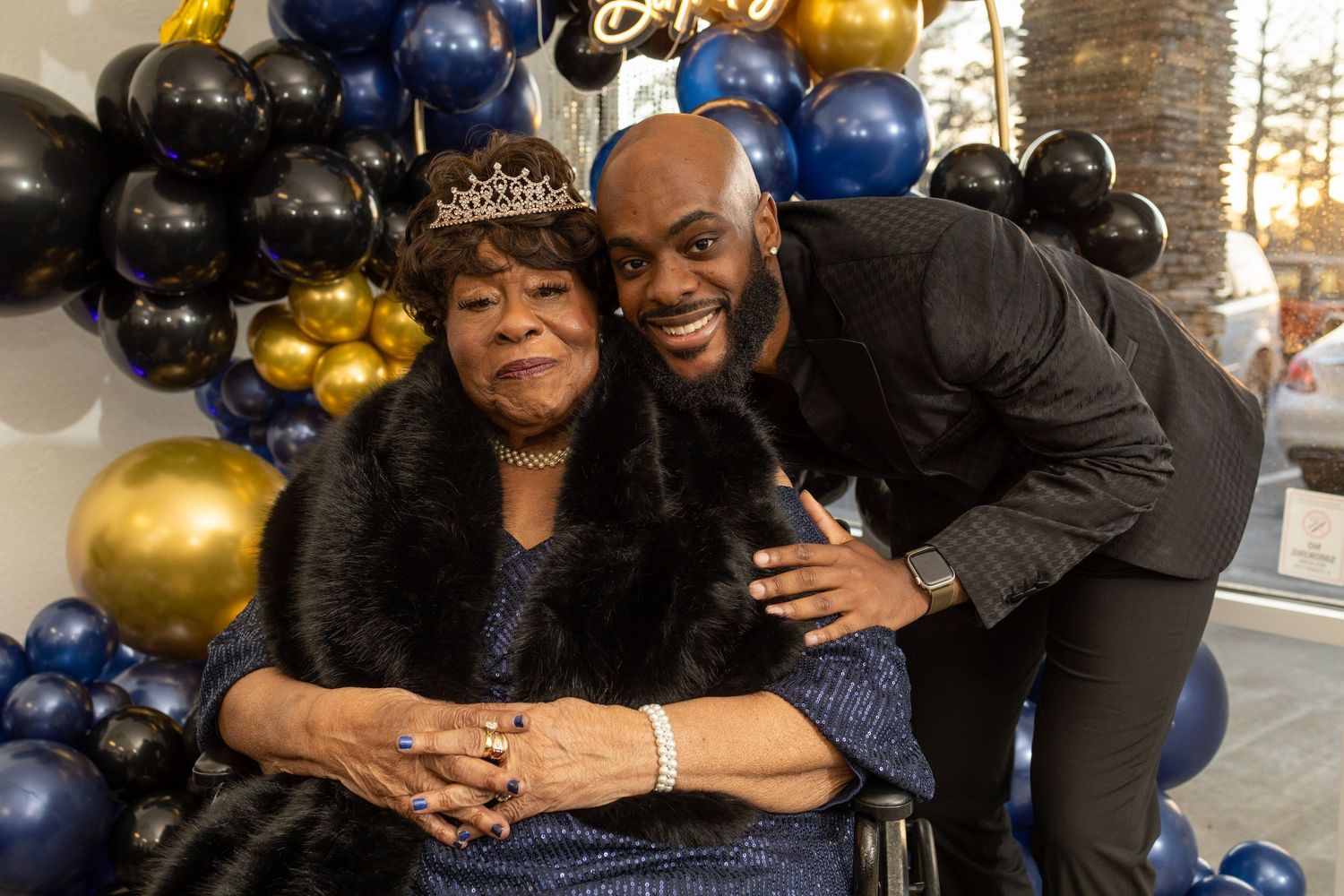 Family members pose together with gold and navy blue balloons during a celebration event.