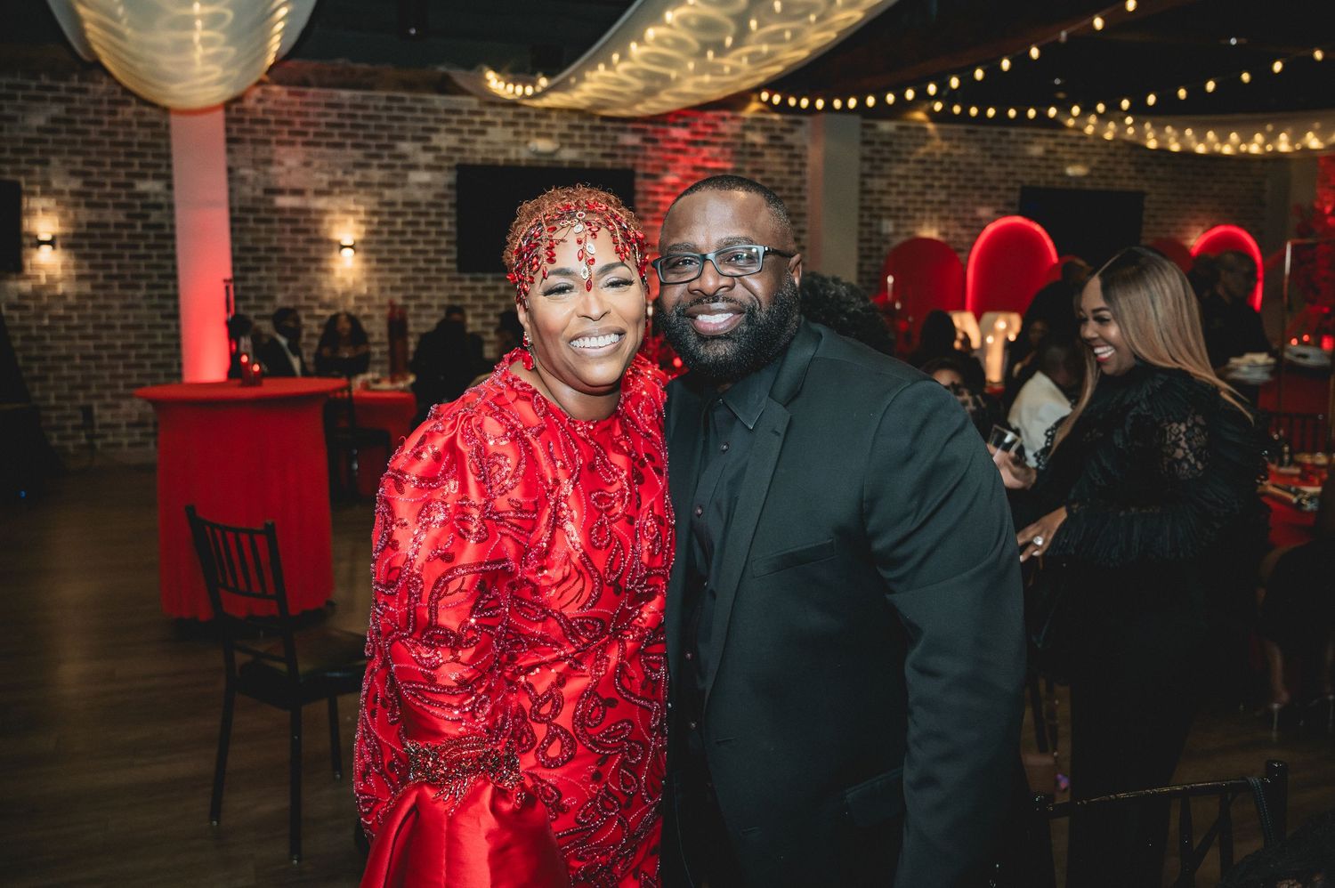 Celebration venue decorated in vibrant red with illuminated marquee letters and party atmosphere.