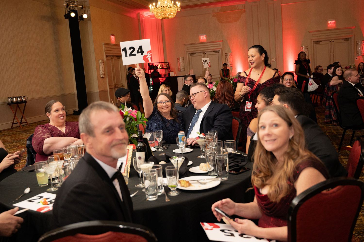 Guests seated at a formal dinner event with table number 124 visible in an elegantly lit ballroom setting.