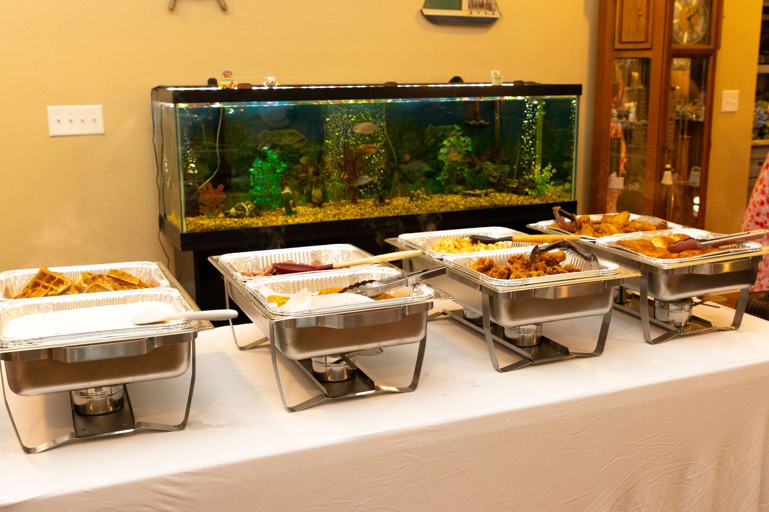 Long buffet table with multiple chafing dishes and food stations for event catering.