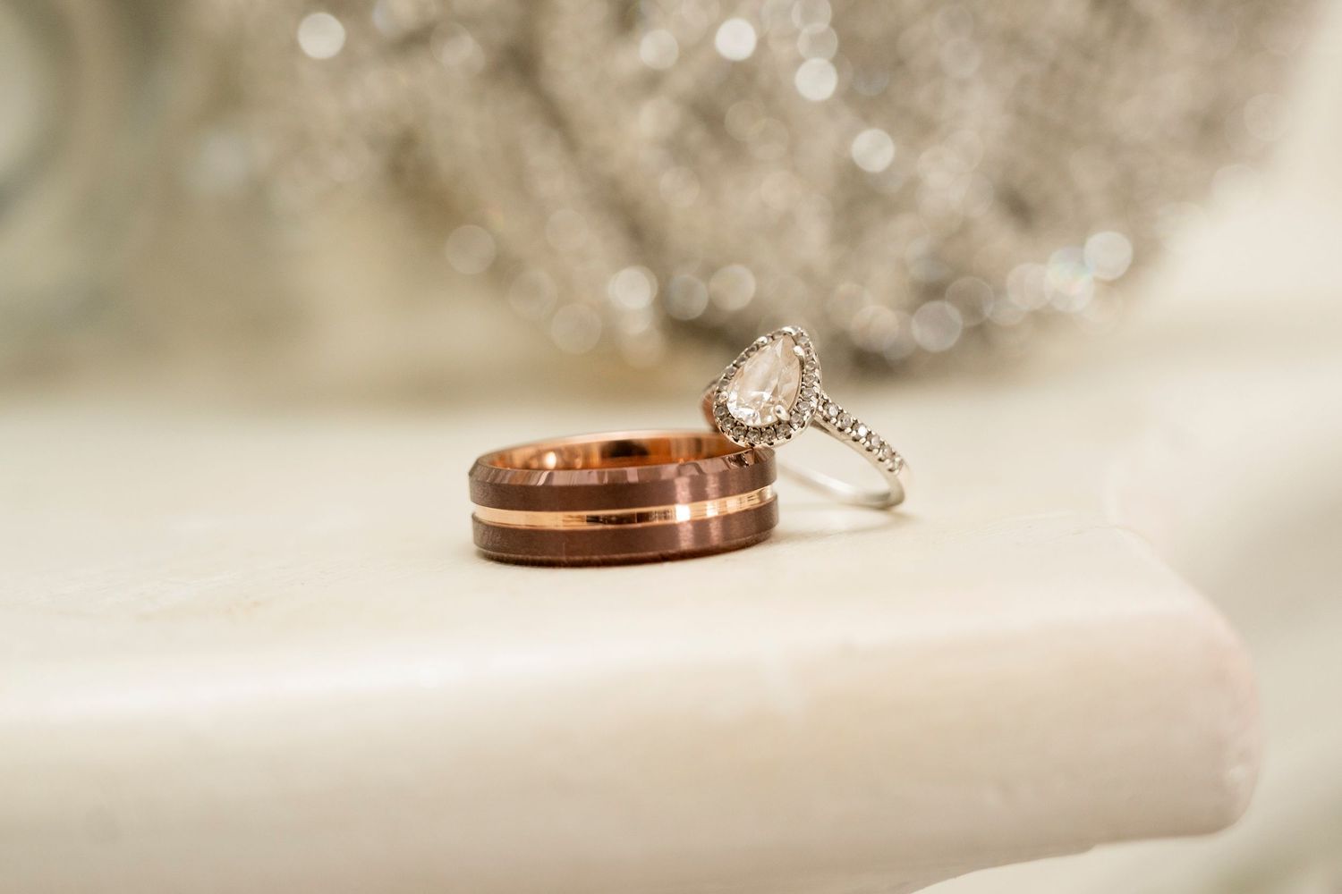 Wedding rings displayed in a row on a soft white surface with delicate bokeh lighting effects in the background.
