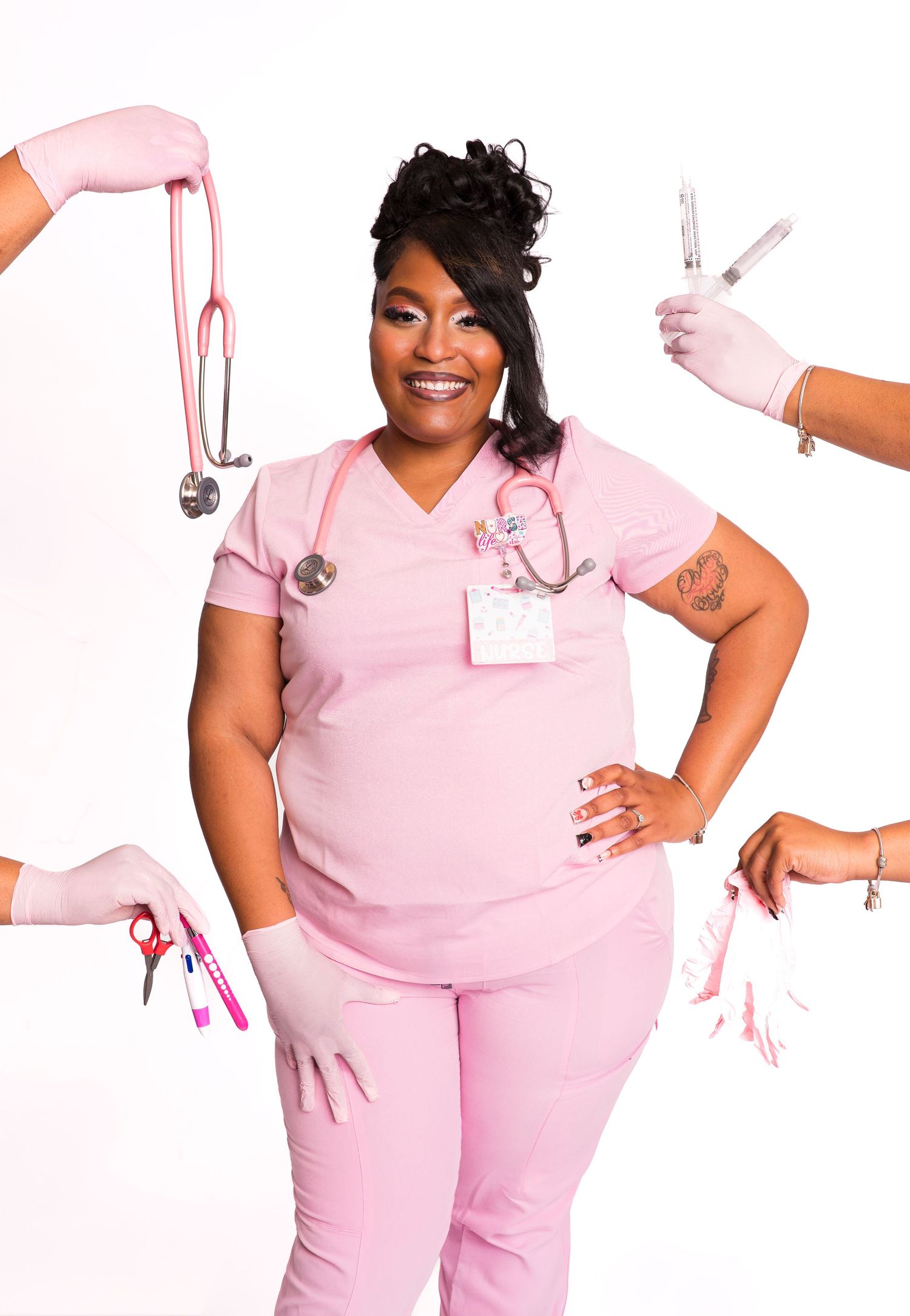 A smiling nurse in pink scrubs poses confidently surrounded by hands holding medical tools including a stethoscope and syringe.