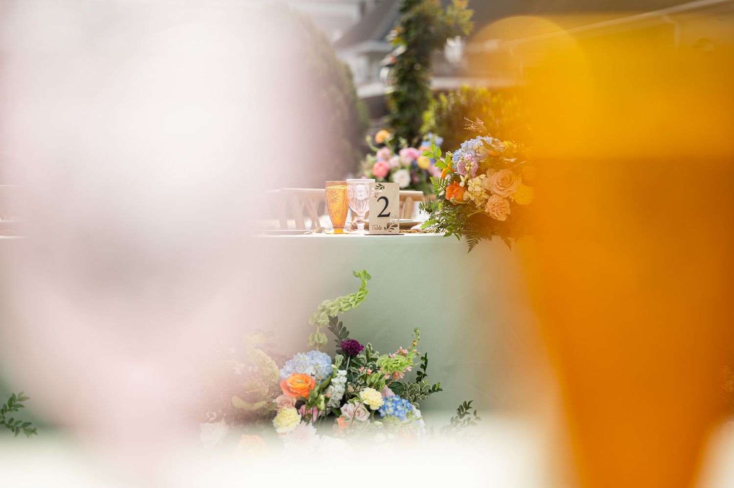Elegant wedding table centerpiece with colorful floral arrangements and decorative number card at a reception.