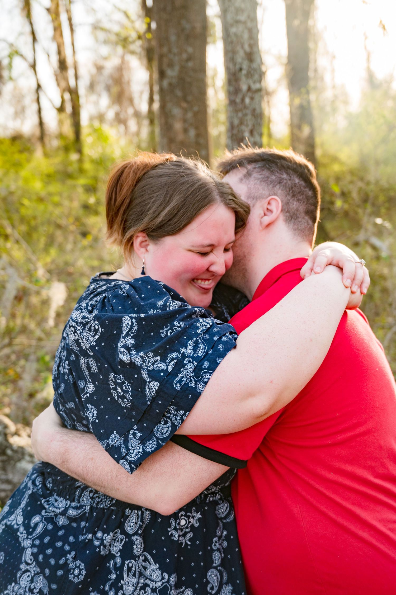 A couple in love shares tender moments in a forest setting with glowing golden sunlight behind them.